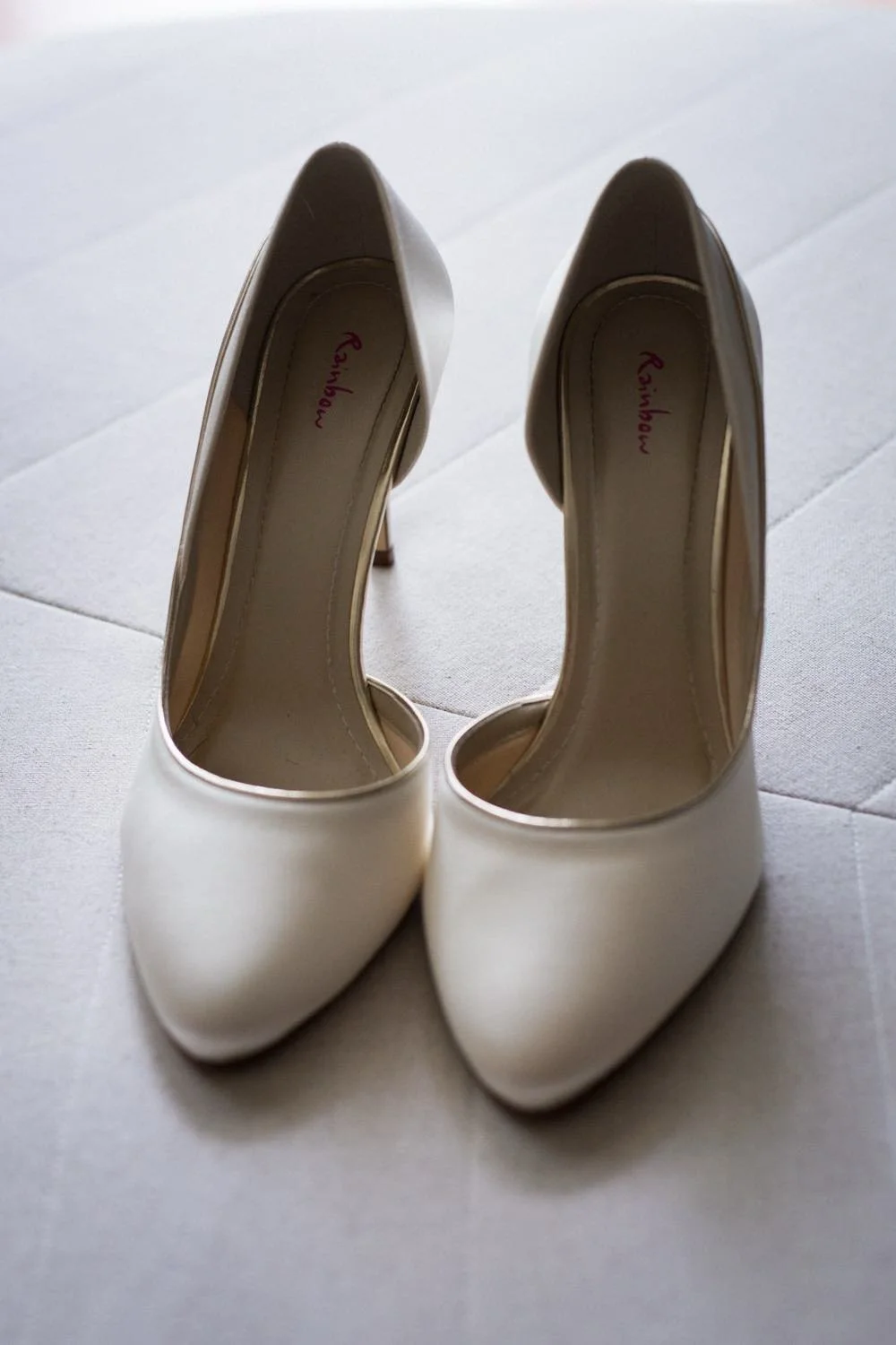 Weiße High Heels auf einem weißen Boden.