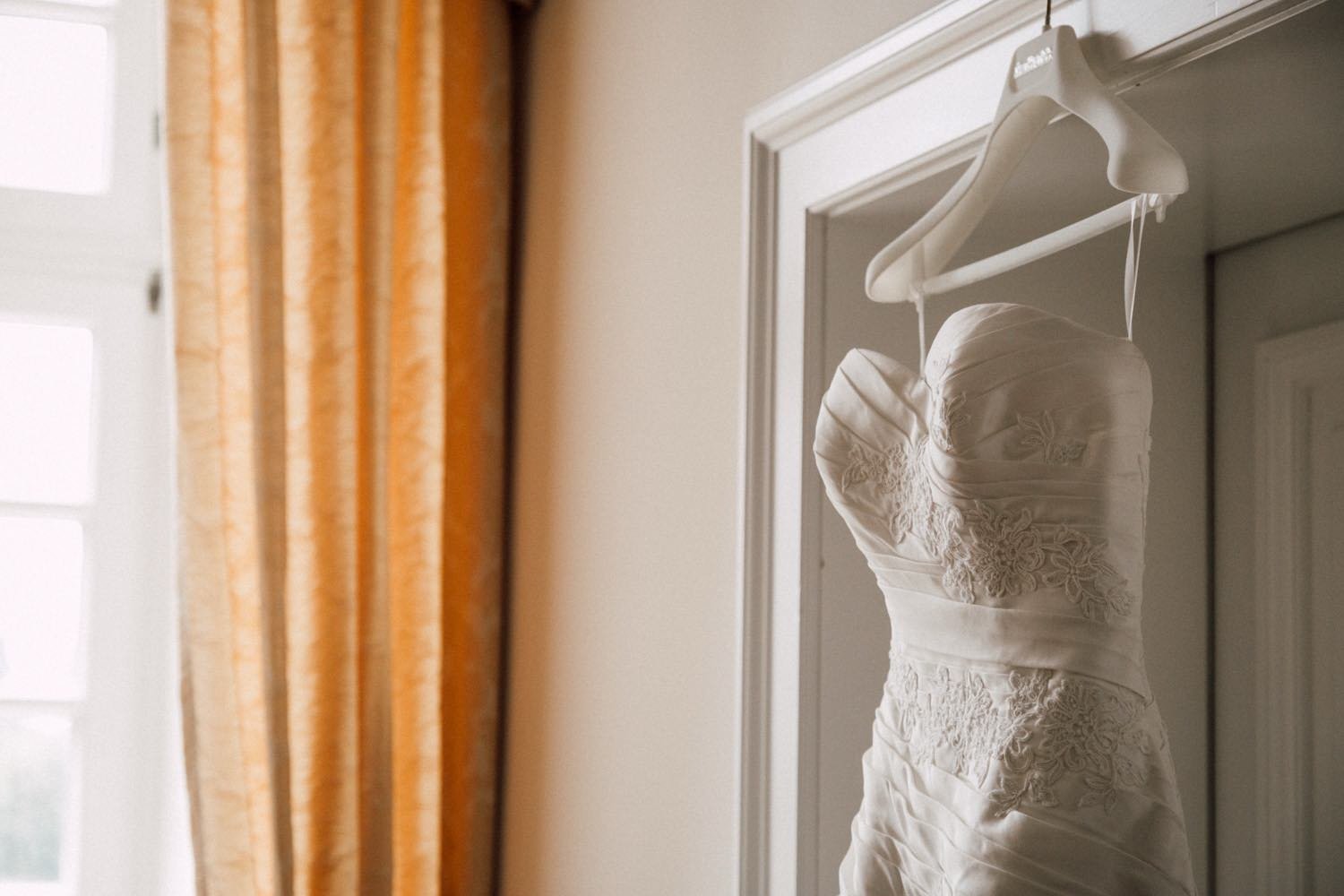Getting Ready – Brautkleid mit Spitzendetails im Hotelzimmer am Kleiderbügel in Darmstadt – von pixelfeder