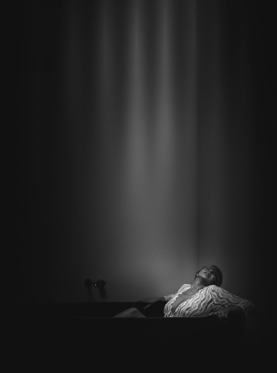 Schwarz-weiß-Foto einer Frau in einer Wanne, die nach oben schaut, mit Lichtstrahlen von oben - pixelfeder