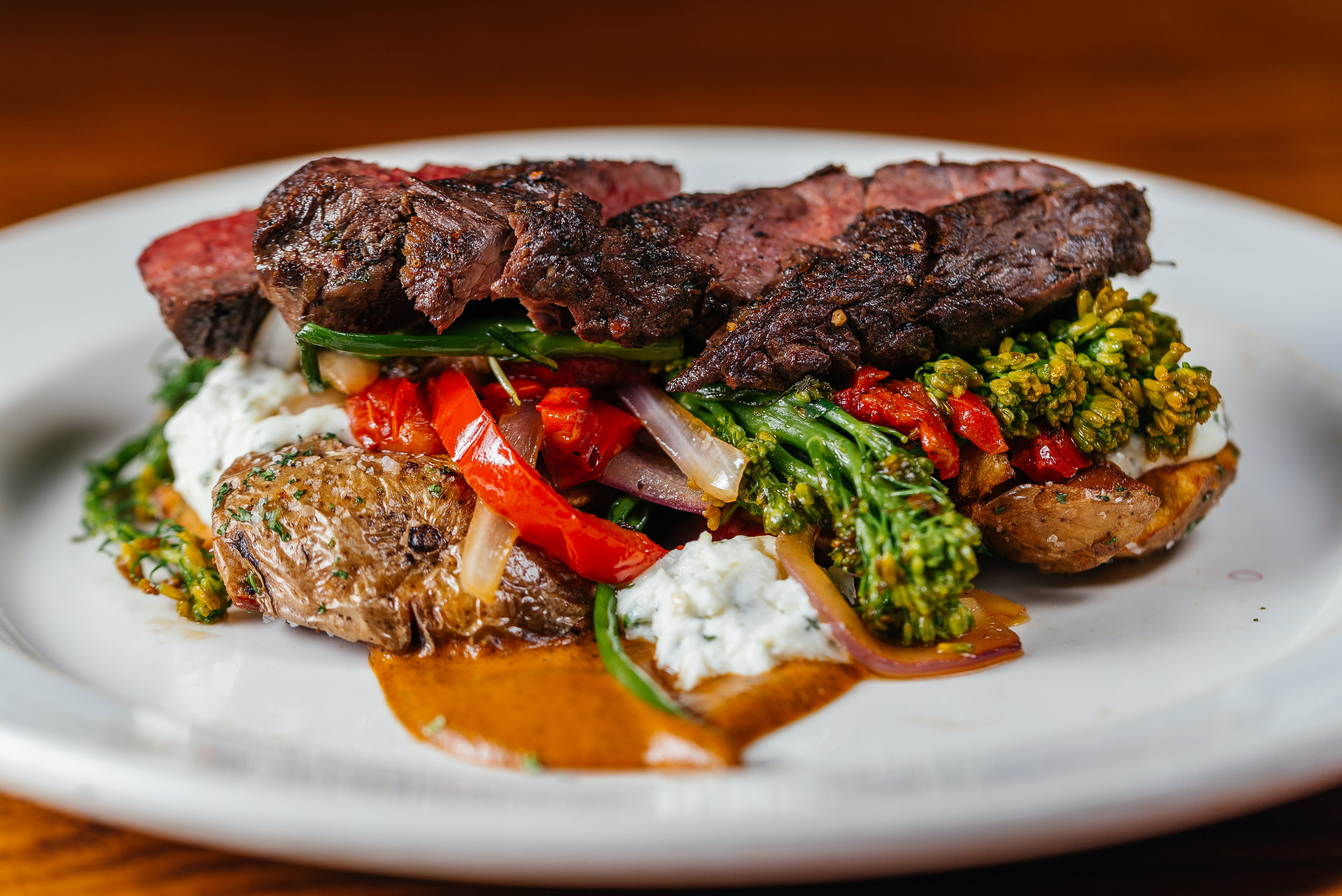 Marinated hanger steak with smashed baby yukons, roasted red peppers, charred onions, and whipped goat cheese