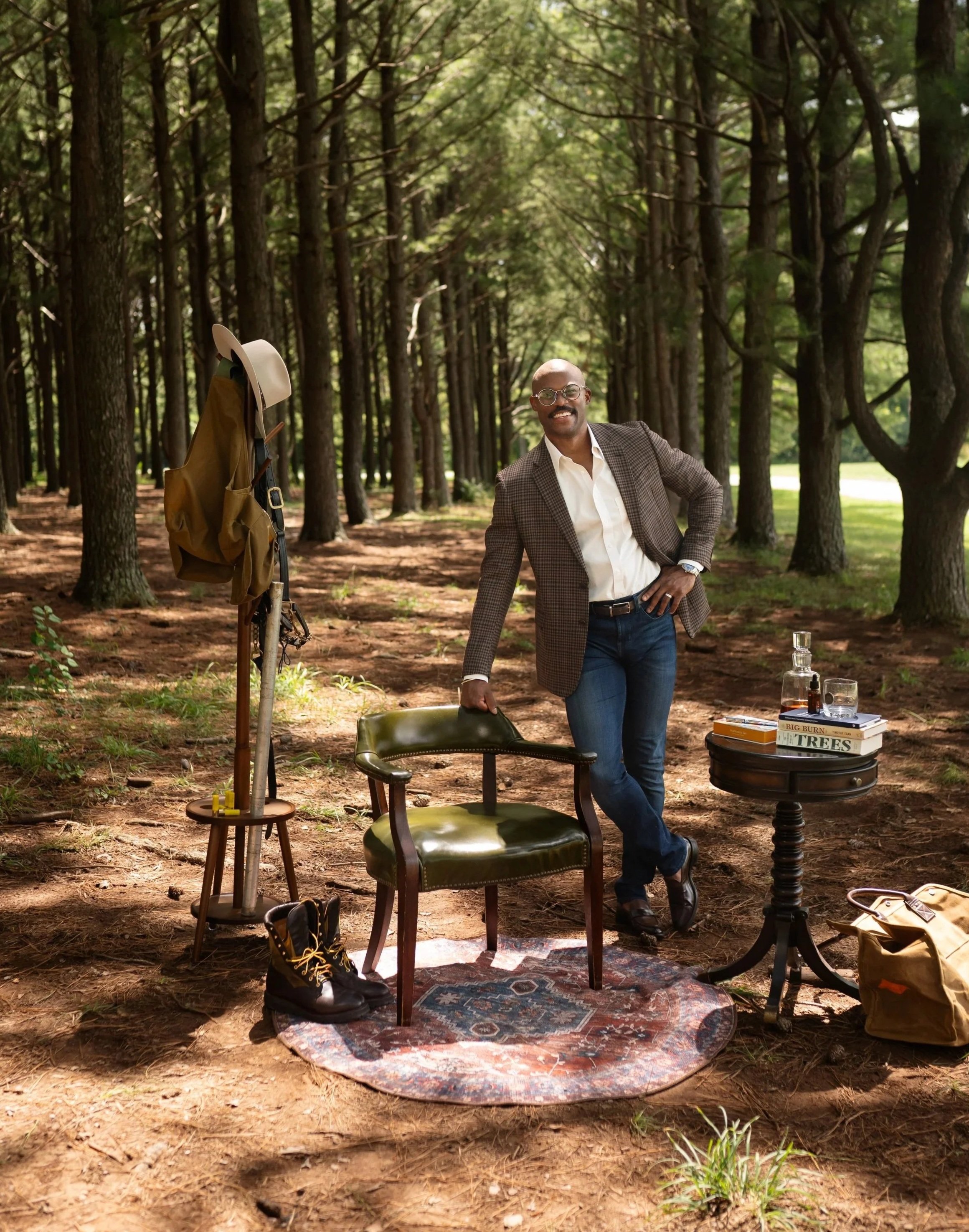 A photo of Stephen standing in the woods, leaning on a chair.