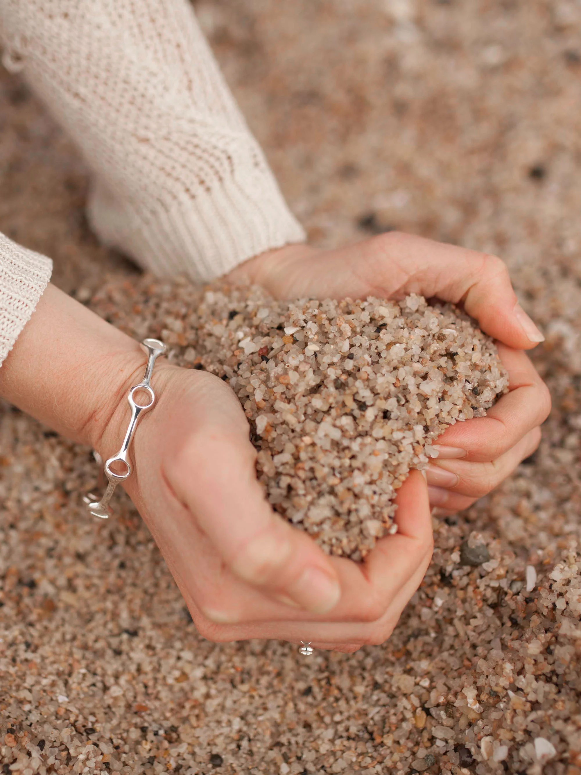 Lunar bracelet worn by model creating love heart in sand