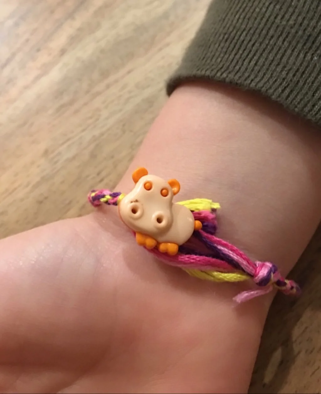 This is a little hippo button with an opening on the reverse that the bracelet was tied to. The slip knot went over the hippo and is adjustable.