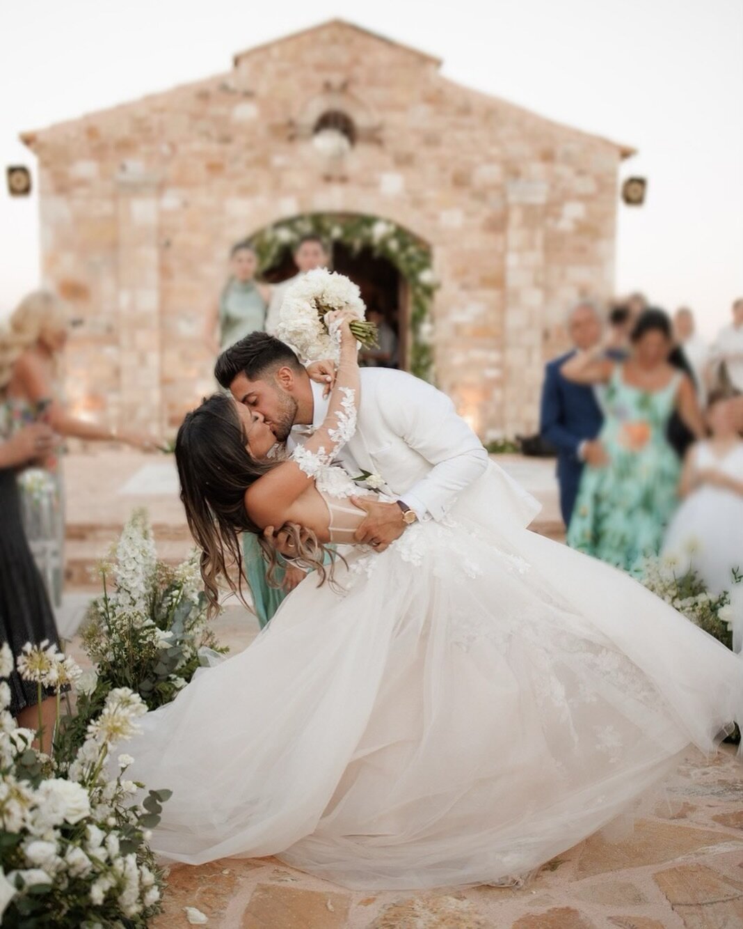 Sealed with a kiss in timeless white. Embrace the allure of Greek romance in our pristine white wedding tuxedo. Elevate your moment of love with effortless sophistication. #silverfoxlabel #wedding #weddinginspiration #weddingtuxedo #destinationweddin