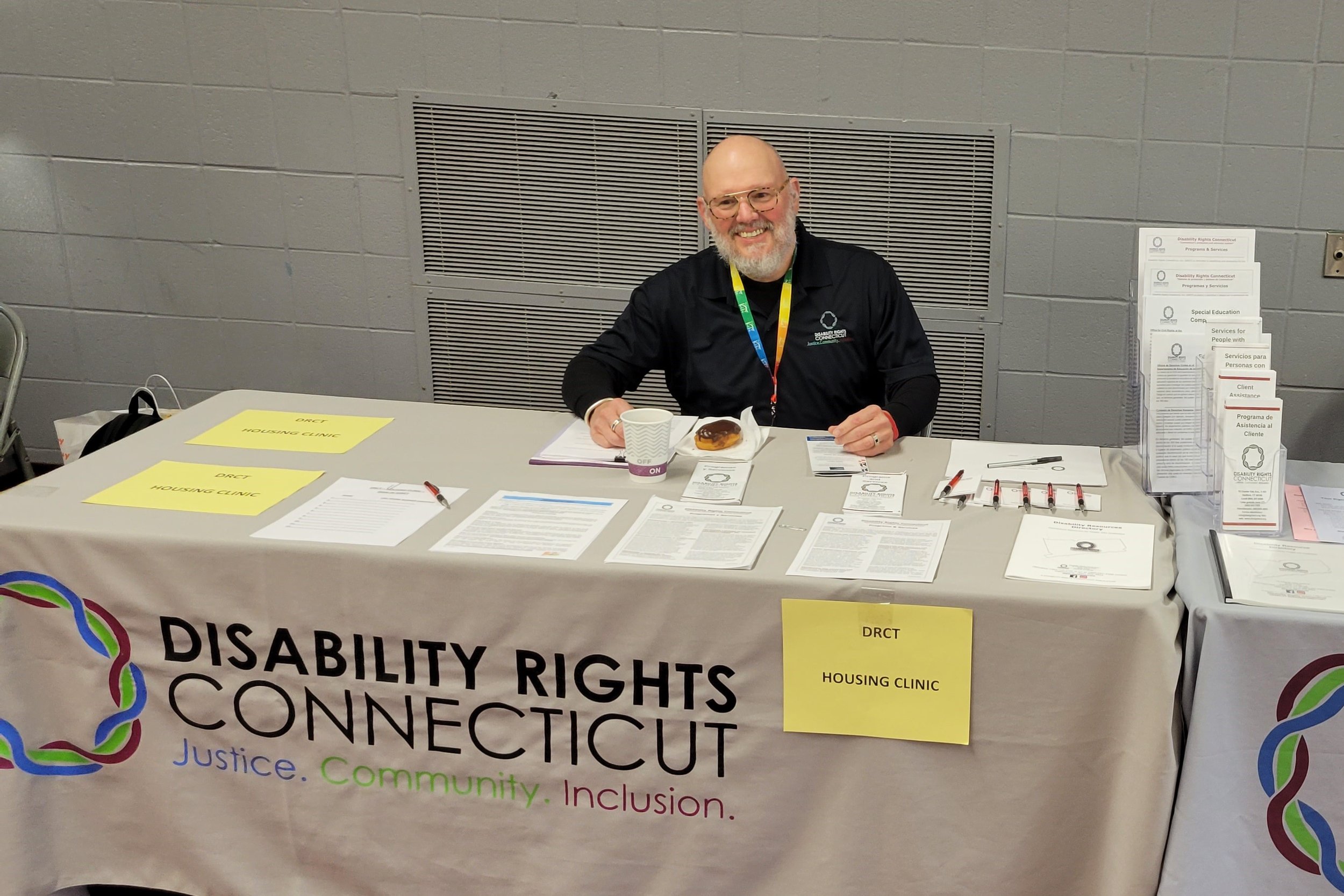   DRCT’s Staff Attorney, Steve Byers sitting down smiling behind DRCT housing clinic table.  