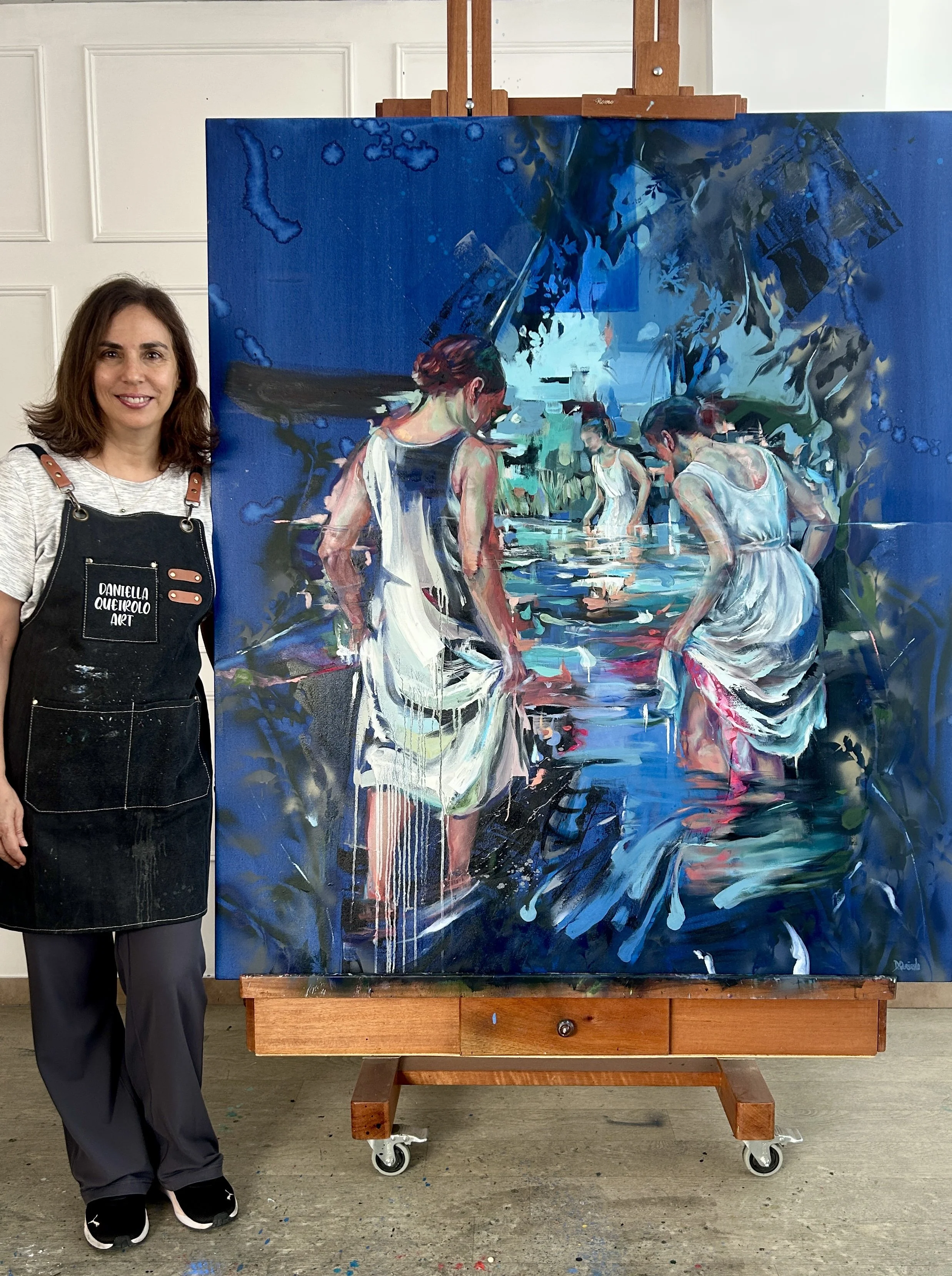 International artist Daniella Queirolo with her last creation. A beautiful oil painting in blue colors depicting an intimite scene of women bathing in a stream.