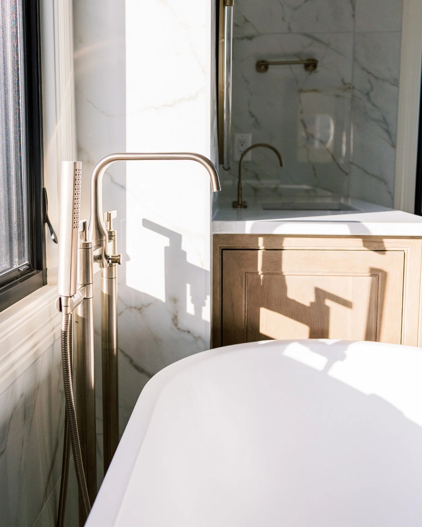Soft morning light + warm brass details ✨

This bathroom was designed to feel like a true retreat &mdash; calm, elevated, and quietly luxurious. The freestanding tub sets the tone, framed by floor-to-ceiling marble that wraps the space in soft moveme