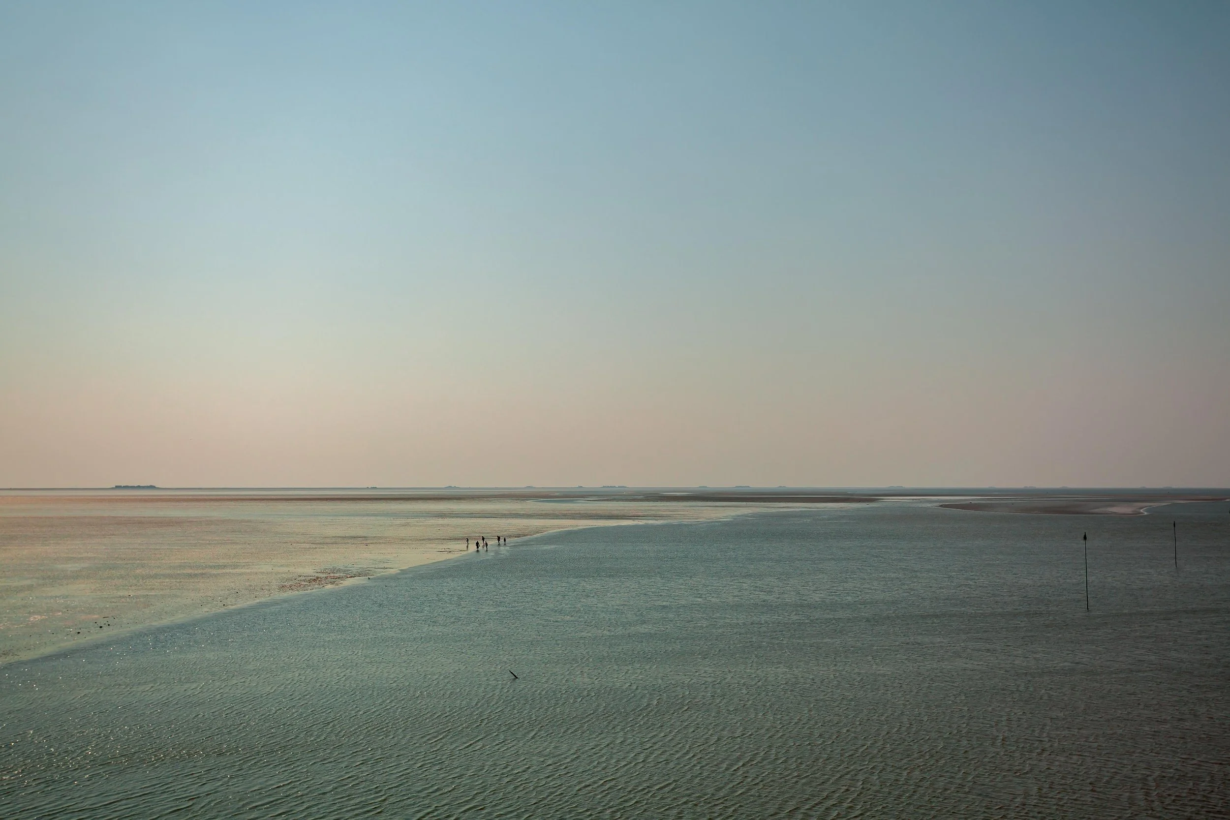People wade in shallow waters on the side of the narrow channel between Esbjerg and Fanø, Denmark