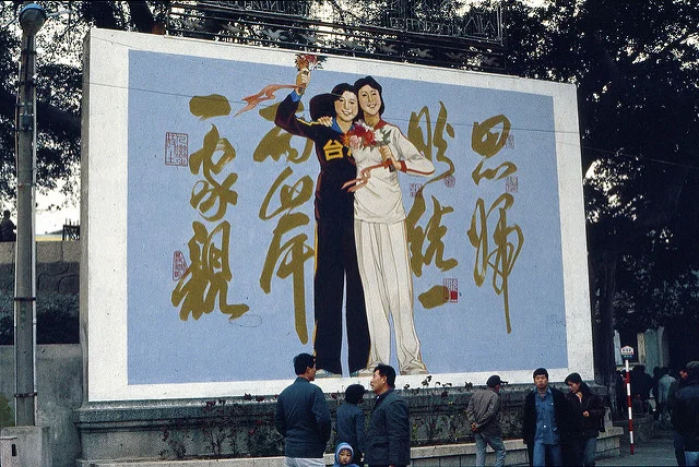 Image: China & Taiwan: 2 sisters, Large propaganda board with China and Taiwan depicted as two sisters, happily holding each other in Xiamen, PRC: 思归照统一,两岸一家亲, kattebelletje , CC BY-NC 2.0
