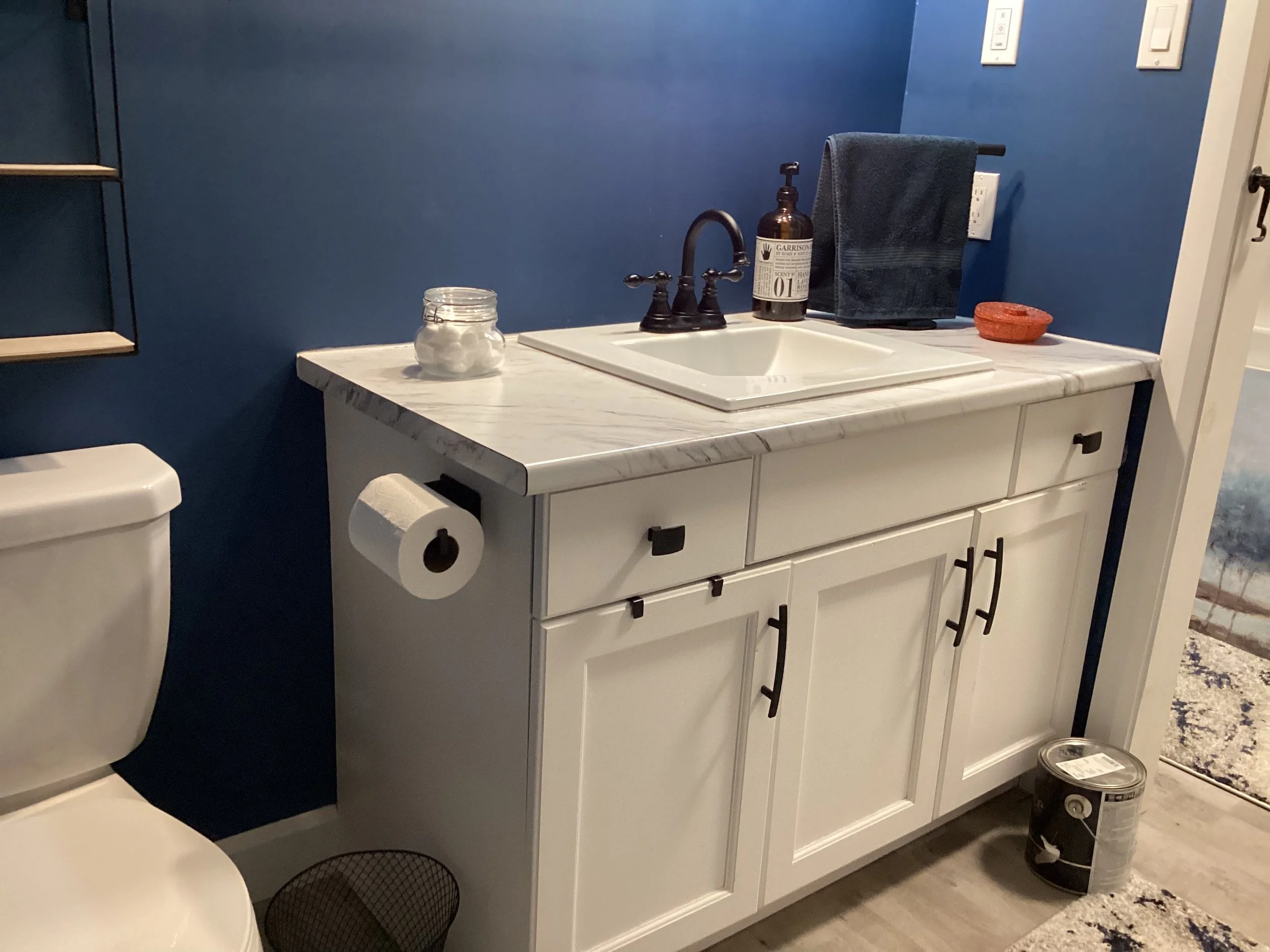 white bathroom vanity next to white toilet with royal blue walls ready for painting
