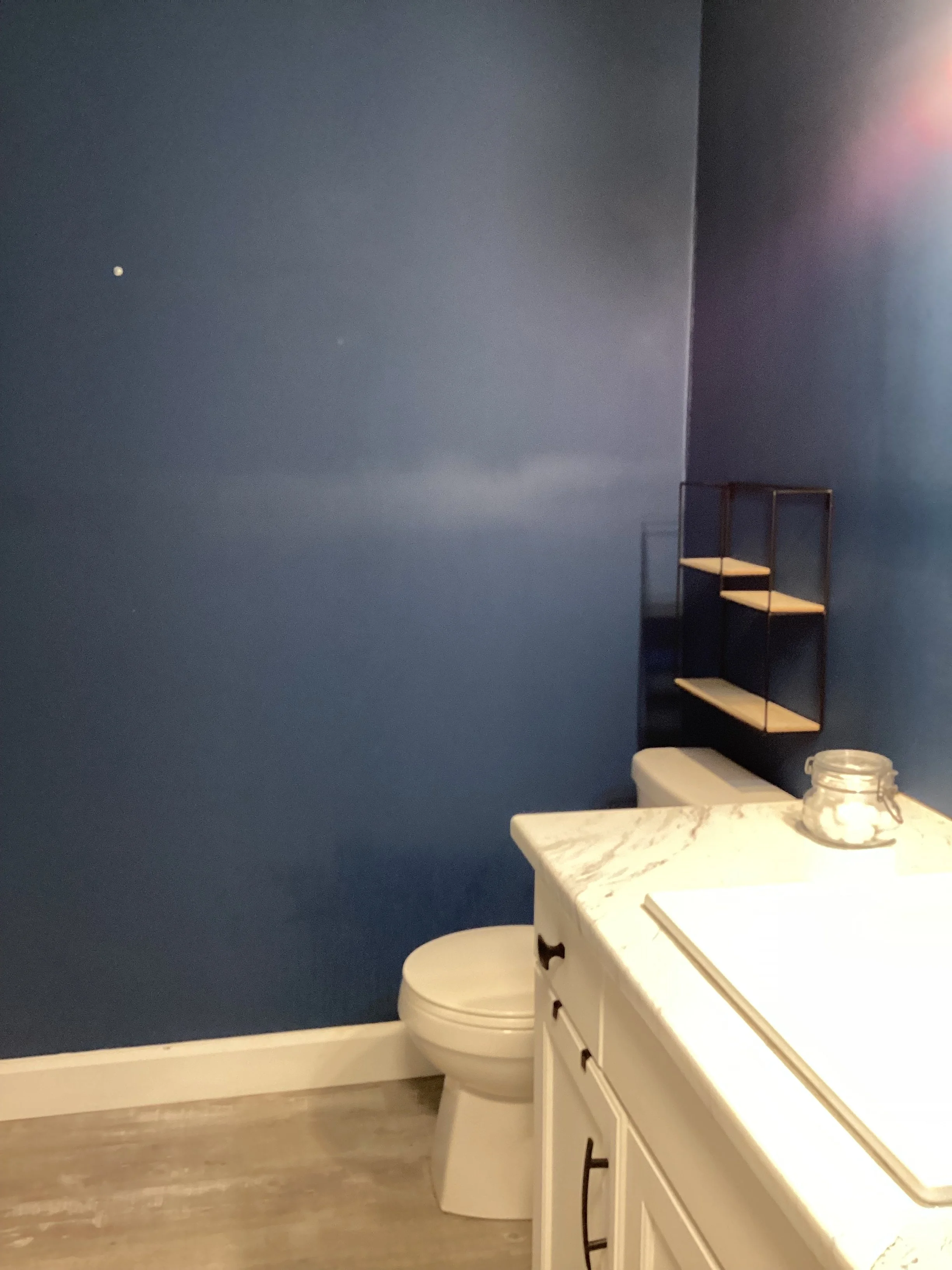 royal blue bathroom walls empty wall shelf and white toilet