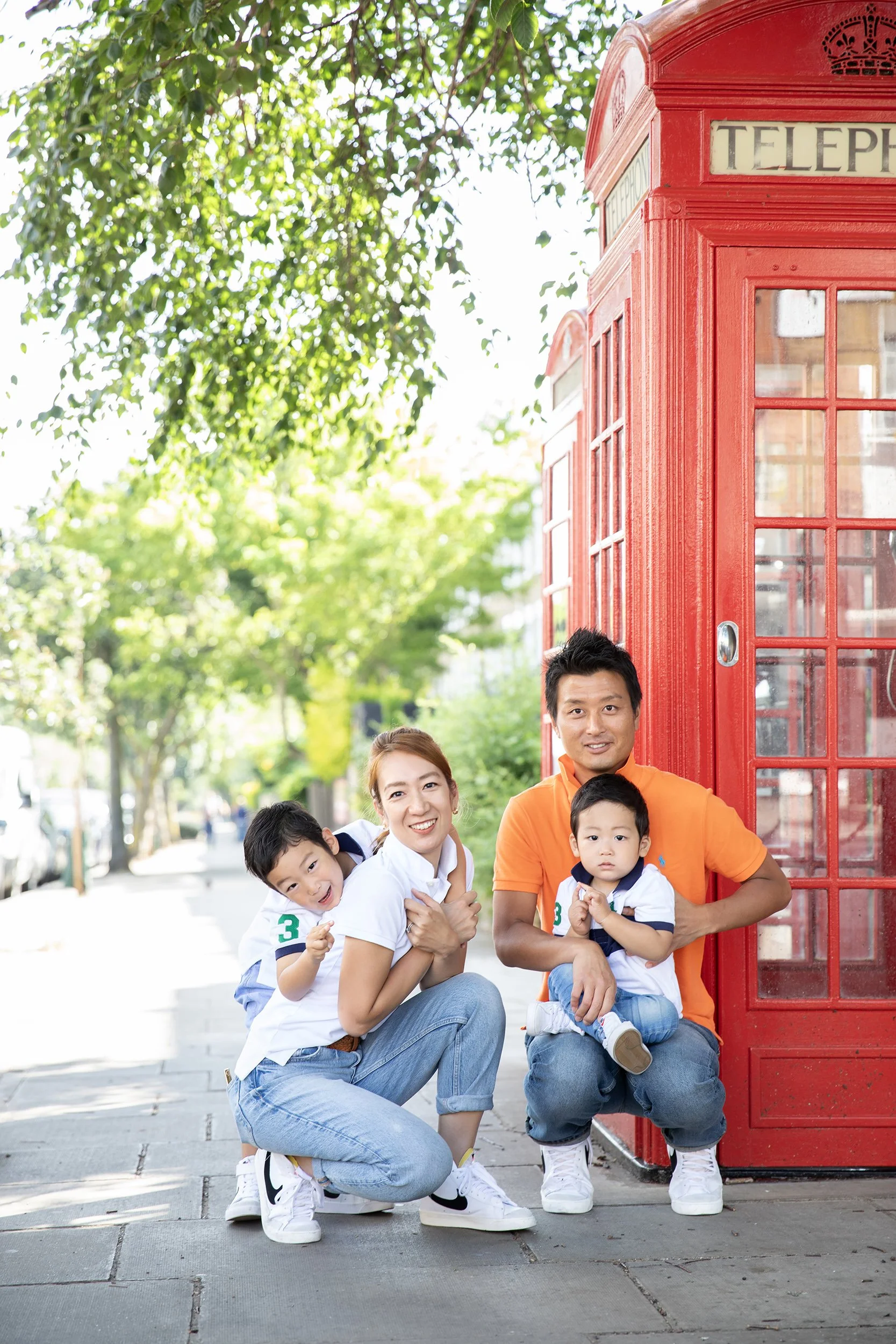 a family of hour next to a red phonebox