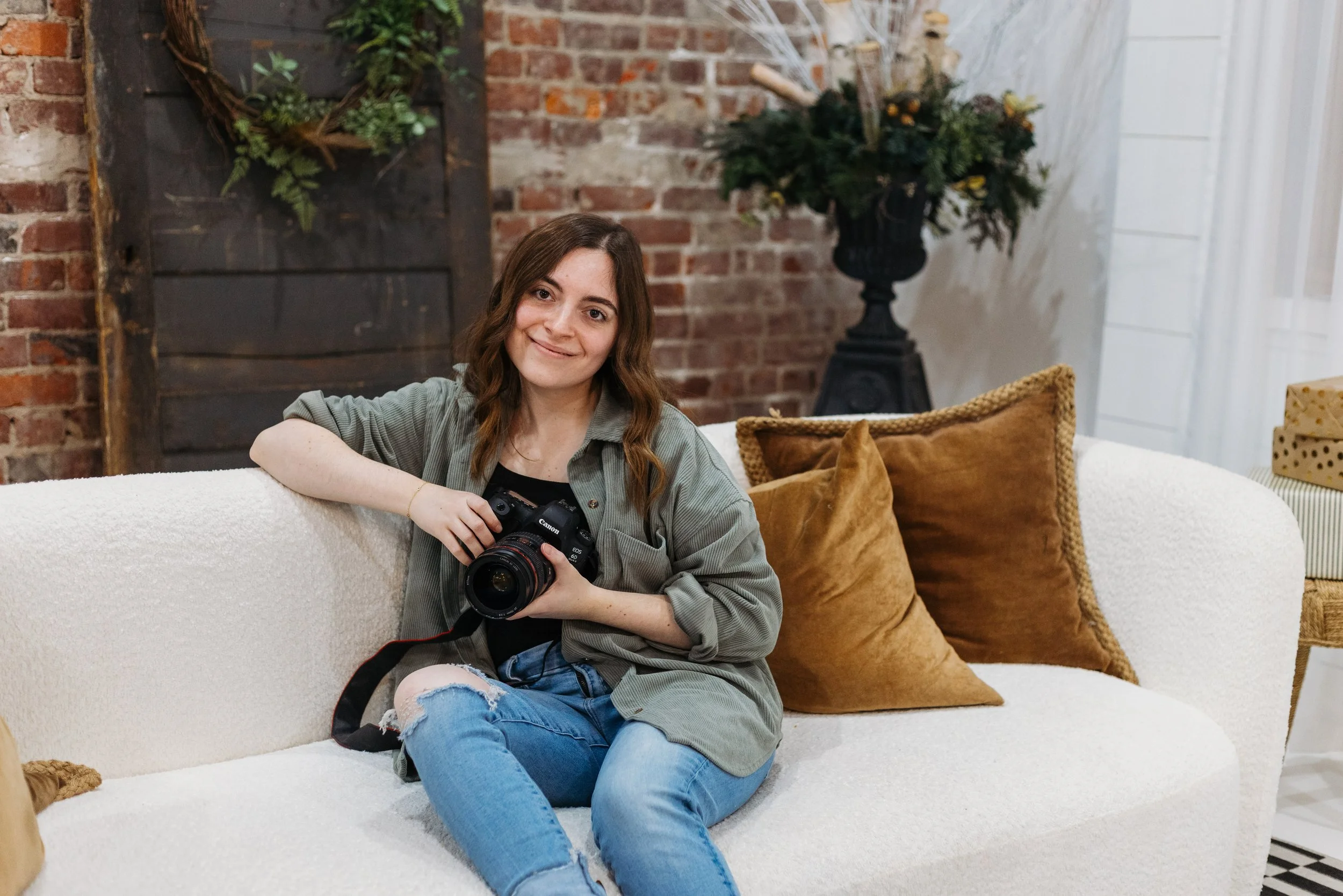Zoie sitting on a couch with camera in hand.