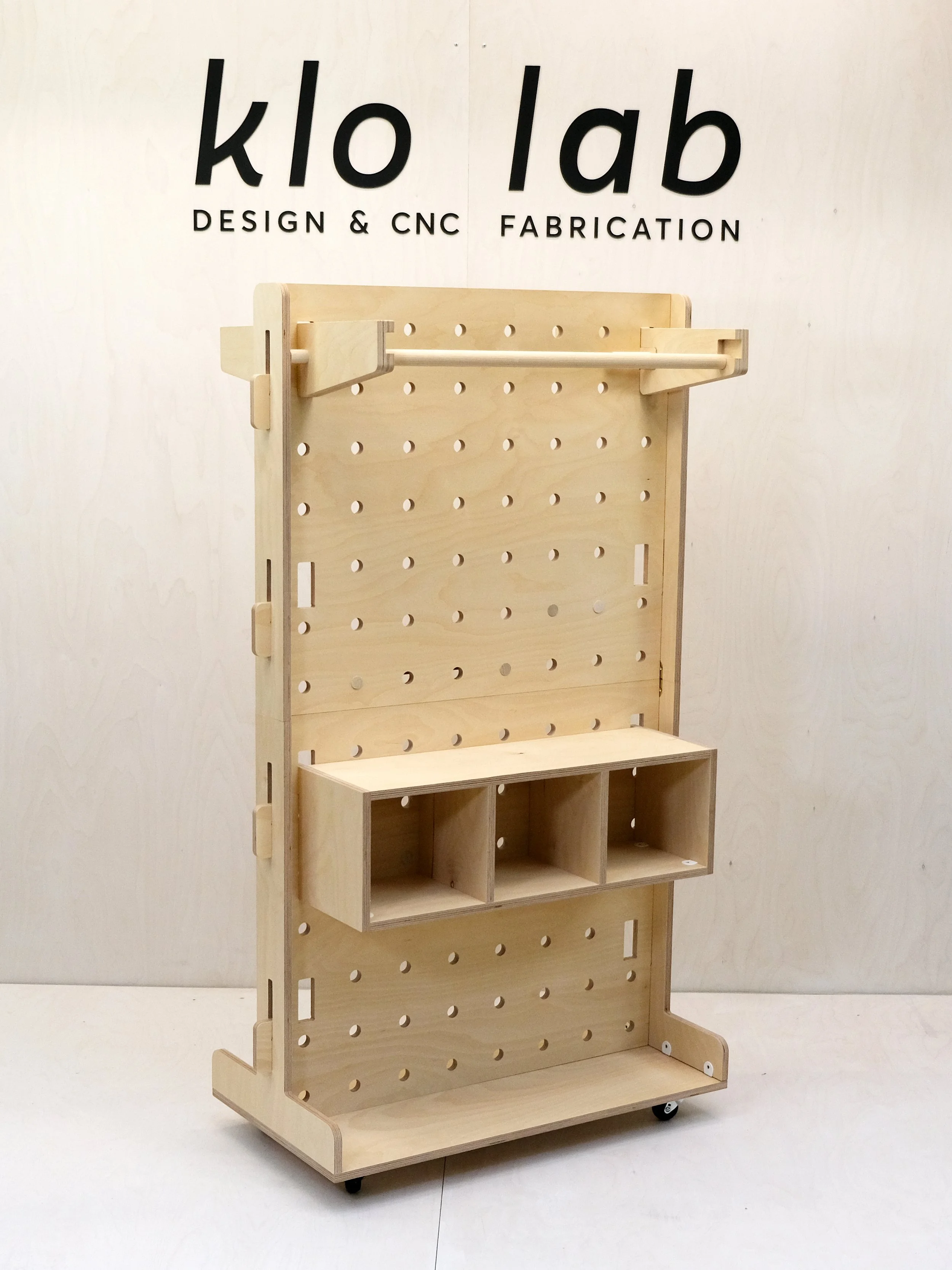 Compact birch plywood pegboard unit with storage cubbies and double sided garment bar