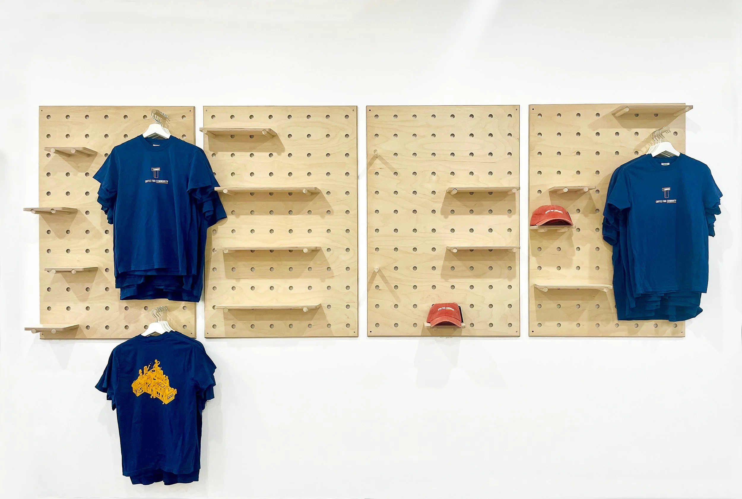 Cafe retail merchandising wall using pegboard shelves for hats and tshirts