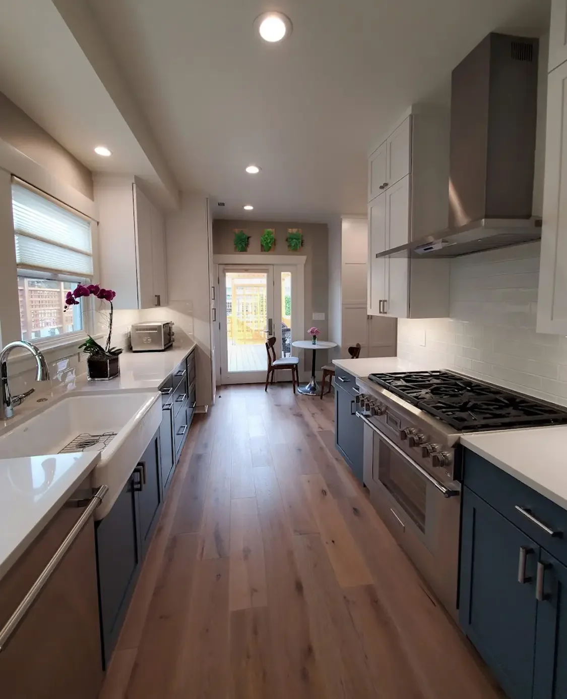 Modern kitchen with Huntwood cabinets, farmhouse sink, stainless steel appliances, Evoke flooring, and preserved fern & moss wall art in rustic reclaimed wood frame.