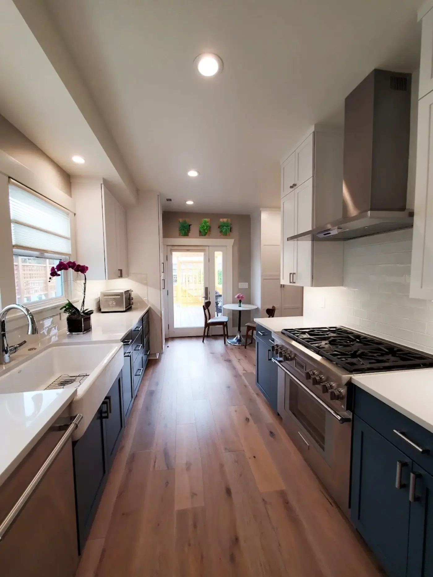 Modern kitchen with Huntwood cabinets, farmhouse sink, stainless steel appliances, Evoke flooring, and preserved fern & moss wall art in rustic reclaimed wood frame.
