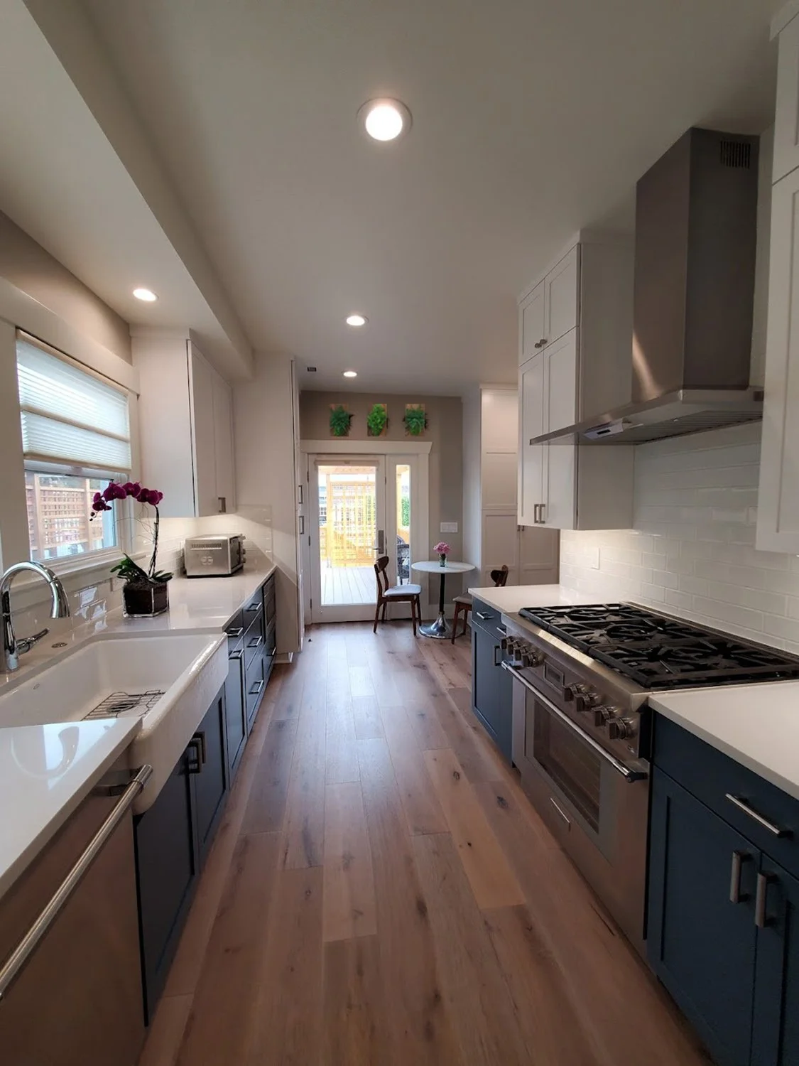 Modern kitchen with Huntwood cabinets, farmhouse sink, stainless steel appliances, Evoke flooring, and preserved fern & moss wall art in rustic reclaimed wood frame.