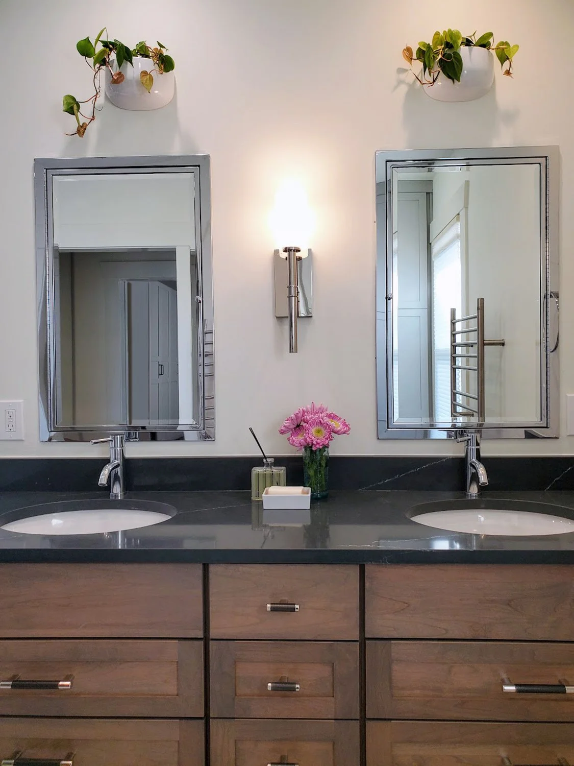 Bathroom with double vanity in Huntwood Montvale cabinets, Soapstone Metropolis over undermount sinks, chrome fixtures, wall plants, and wall‑mounted towel racks.