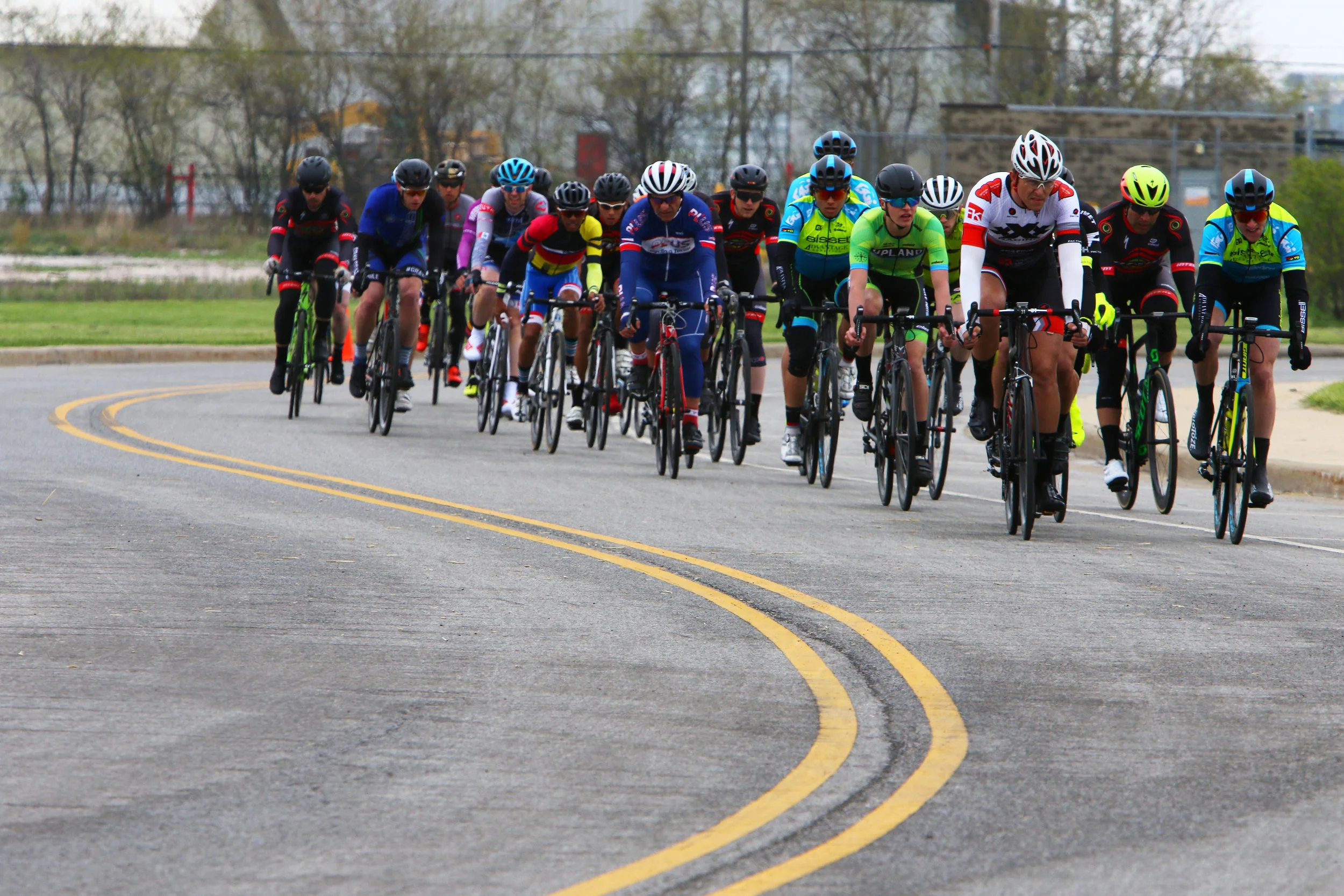 Participants in the men's pro race ride through the course at the Region Riot Criterium bike races at Wolf Lake Pavilion on May 12, 2018 in Hammond.