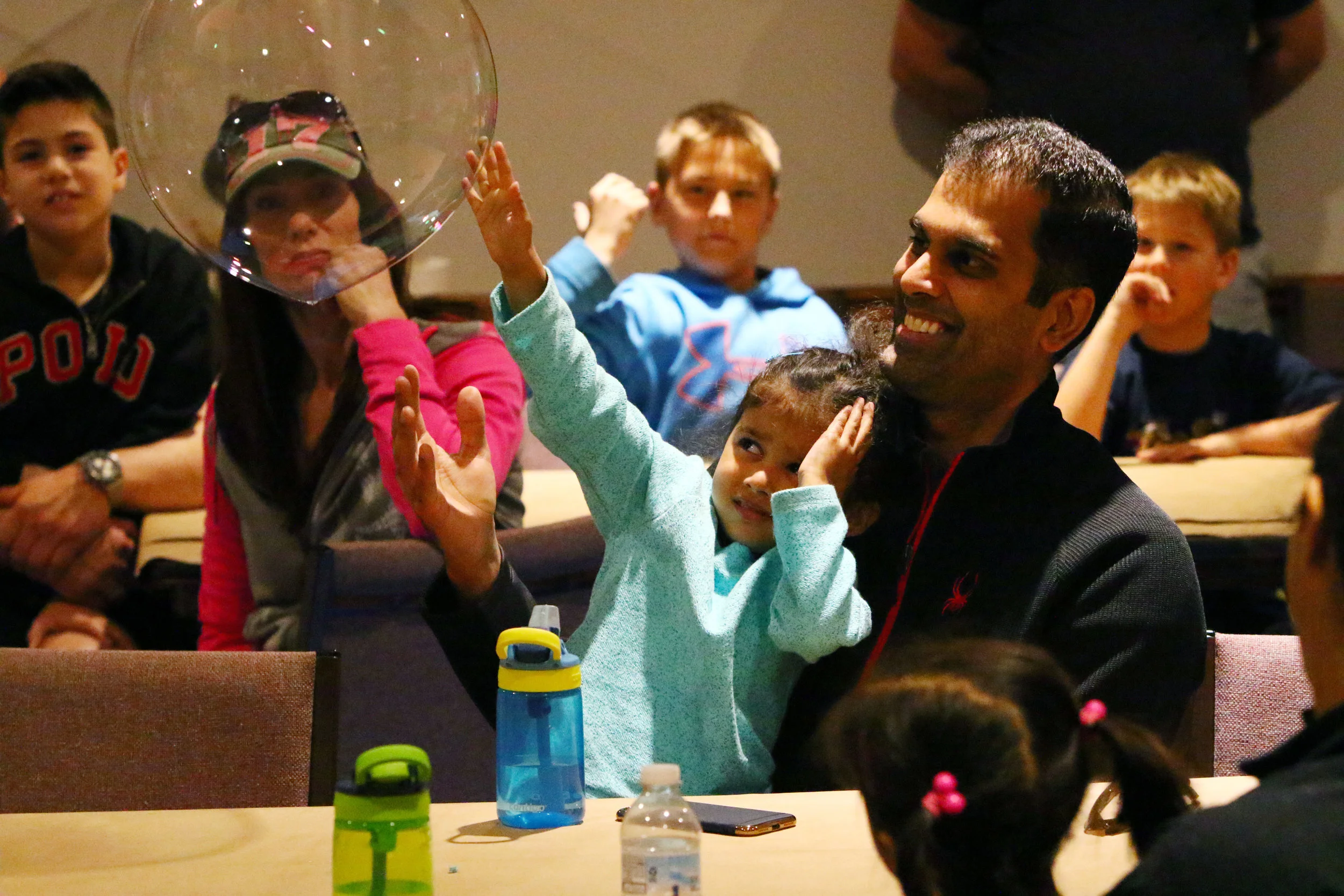 Neel Jain, right, of Chesterton, laughs as his daughter, Sonya, shys away from a bubble floating toward her at the Dunes Learning Center on April 22, 2018 in Chesterton. Families attended a bubble art event led by Mike Bever.