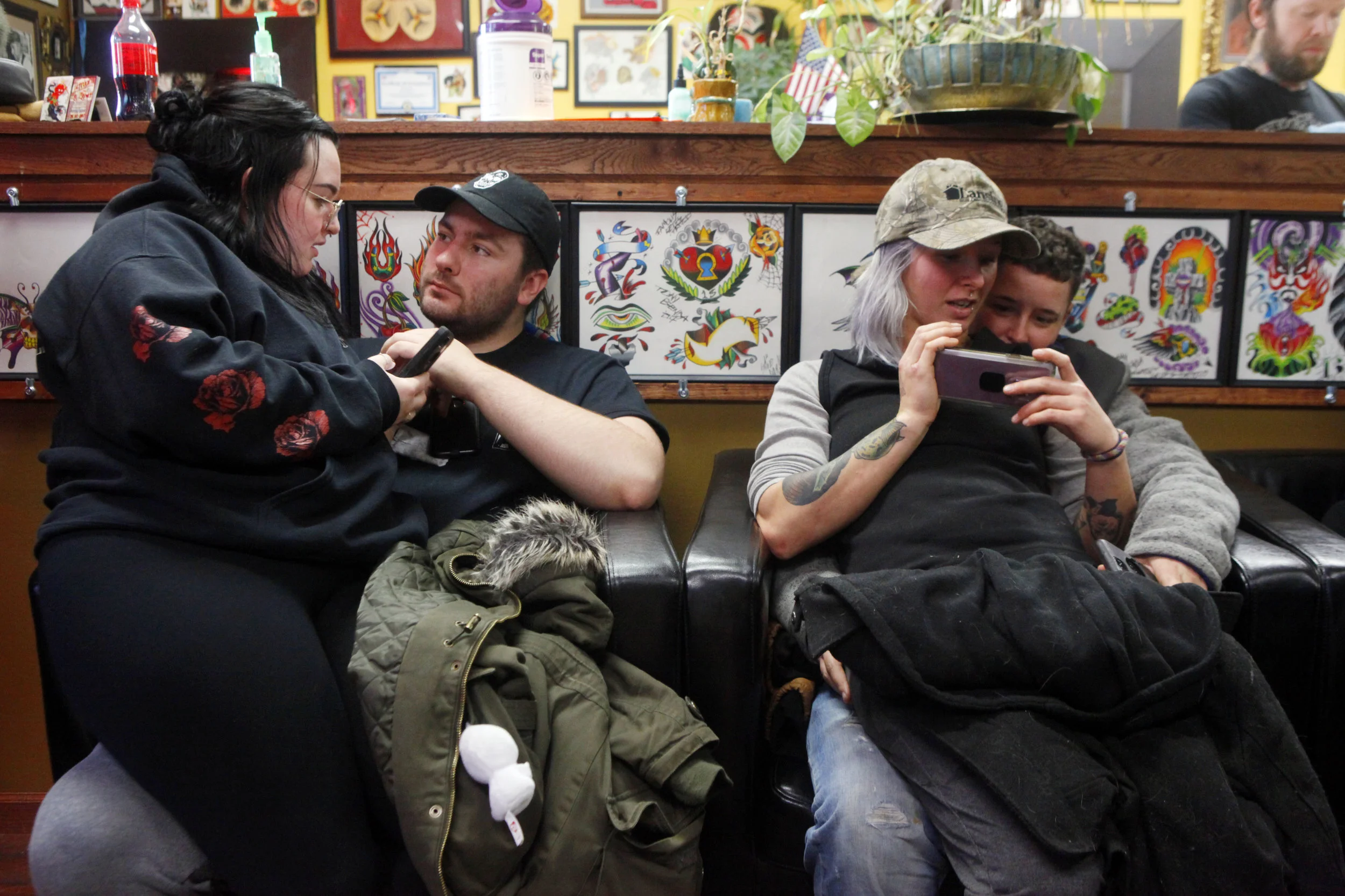 A pair of couples wait their turn to get tattoos at 45th Street Tattoo in Griffith during the business' third annual Toys for Tots event on Dec. 9, 2018. Pictured to the left are Morgan Weidman, of Chicago and Jacob Sylvester, of Crown Point, and to…