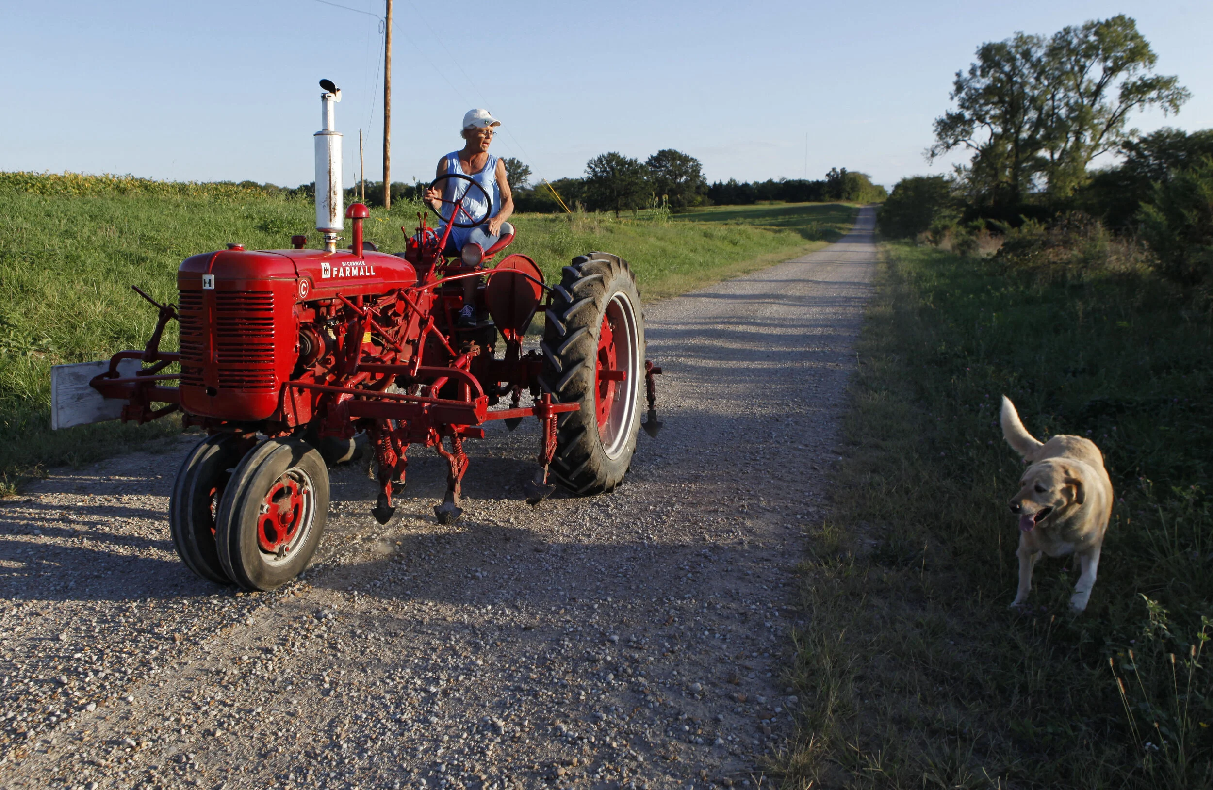  Velma Lang tests one of her tractors on the gravel road that leads to her farm in Syracuse as one of her dogs, Mickey, runs alongside. Lang has worked with repairing and fixing up vehicles since she was a teenager. 