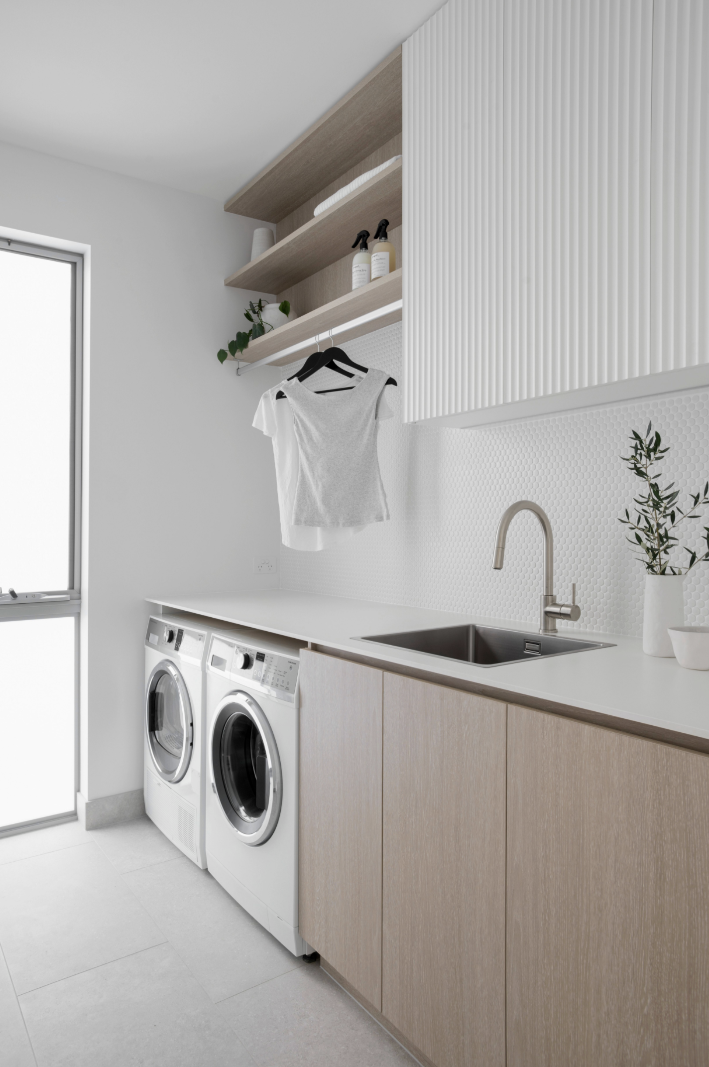 Two washing machine, wooden cabinets and white laundry sink in Contemporary coastal laundry design plan for laundry renovation Melbourne