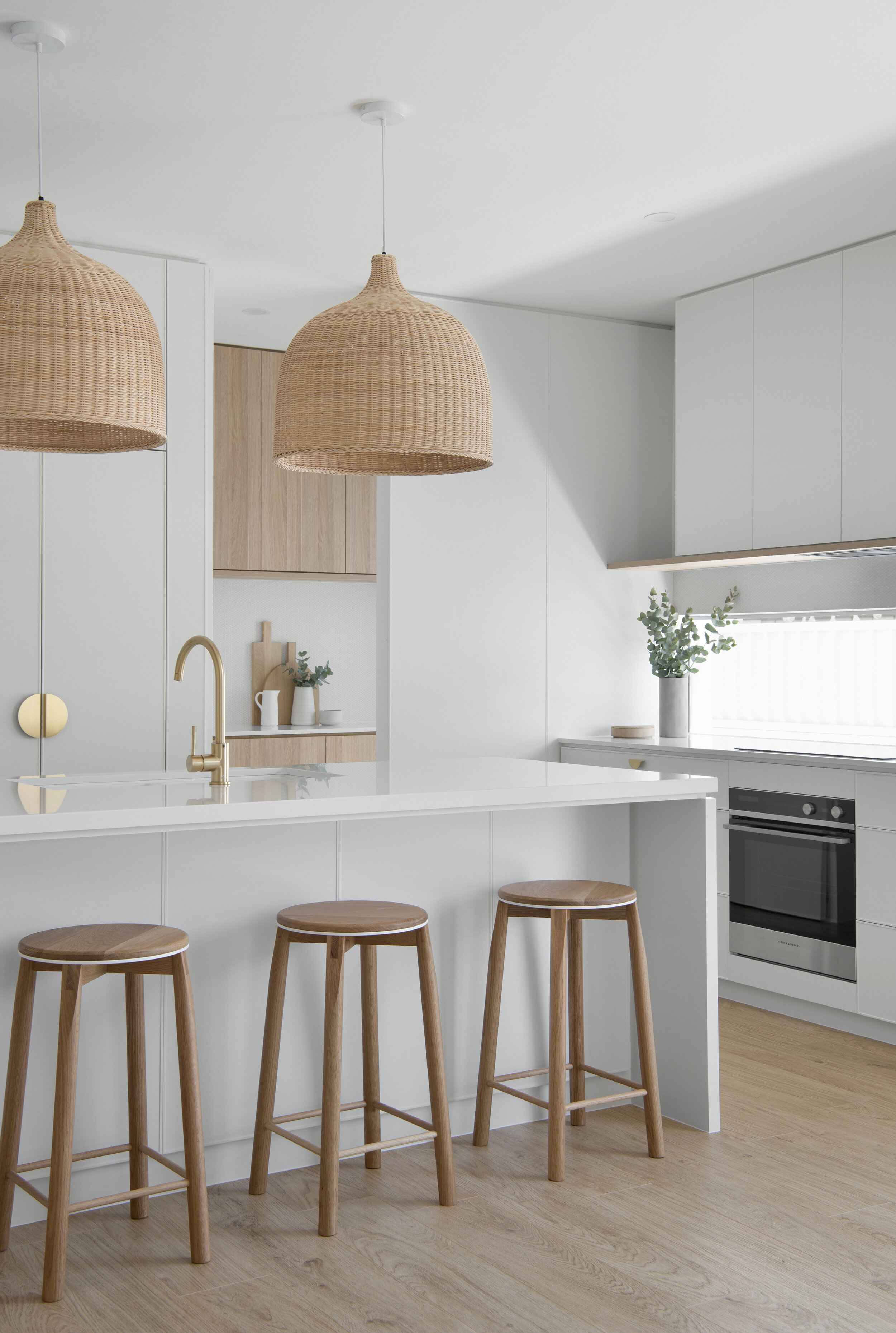 White centre counter with long wooden stools and two celling hanging lights from the classic coastal kitchen design project in classic coastal home design bundle for home remodel