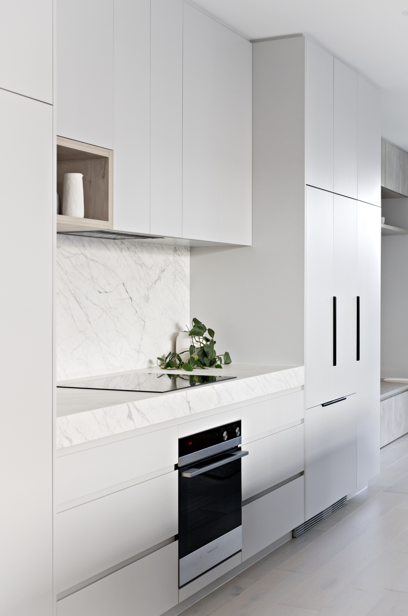 Marble counter with induction stove on top and oven on the atom with plant pot in the background in Scandinavian kitchen design project included in scandi home design bundle scandi kitchen design