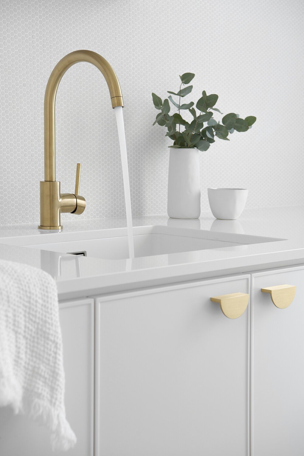 Brass laundry sink faucet with white plant pot in the background in Classic Coastal Laundry laundry room remodel