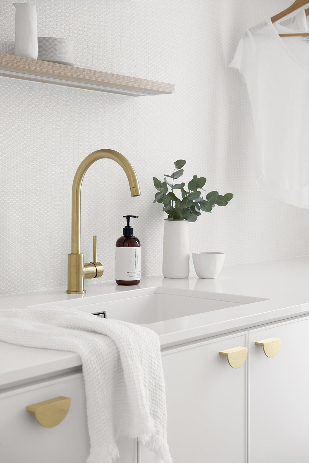 Brass laundry sink faucet with white plant pot in the background in Classic Coastal Laundry Plan for laundry room remodel