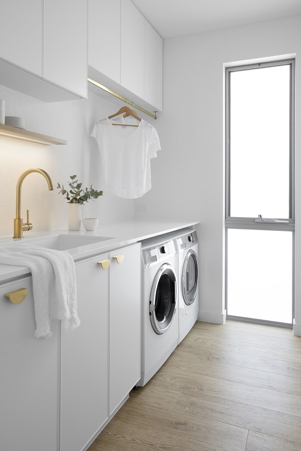 Two washing machine and brass faucets in Classic Coastal Laundry for laundry room remodel