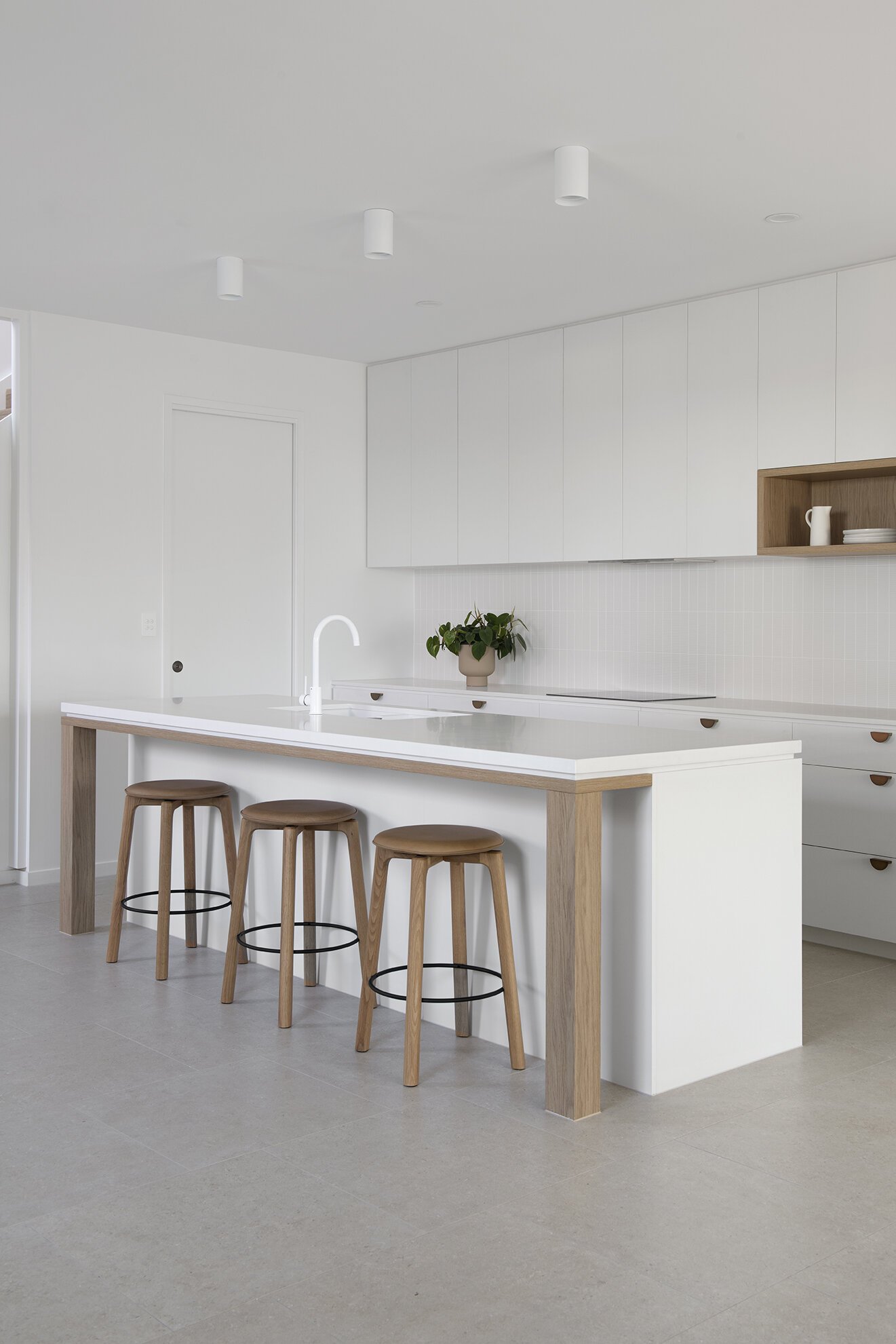 White kitchen island bench with wooden stools and white kitchen cabinets in coral house design bundle for home remodel