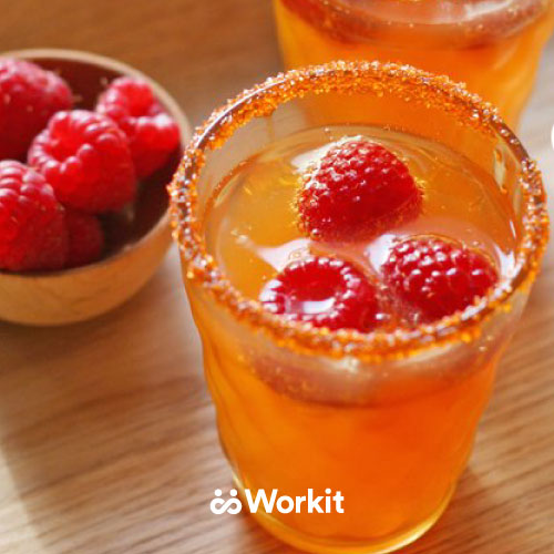 orange mocktail with cranberry garnish and sugar on the glass rim