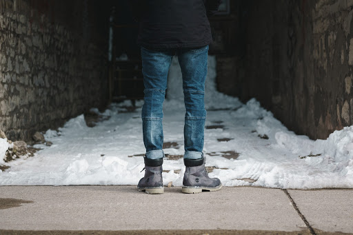 View of a person's booted feet as they face a narrow alley full of snow. 