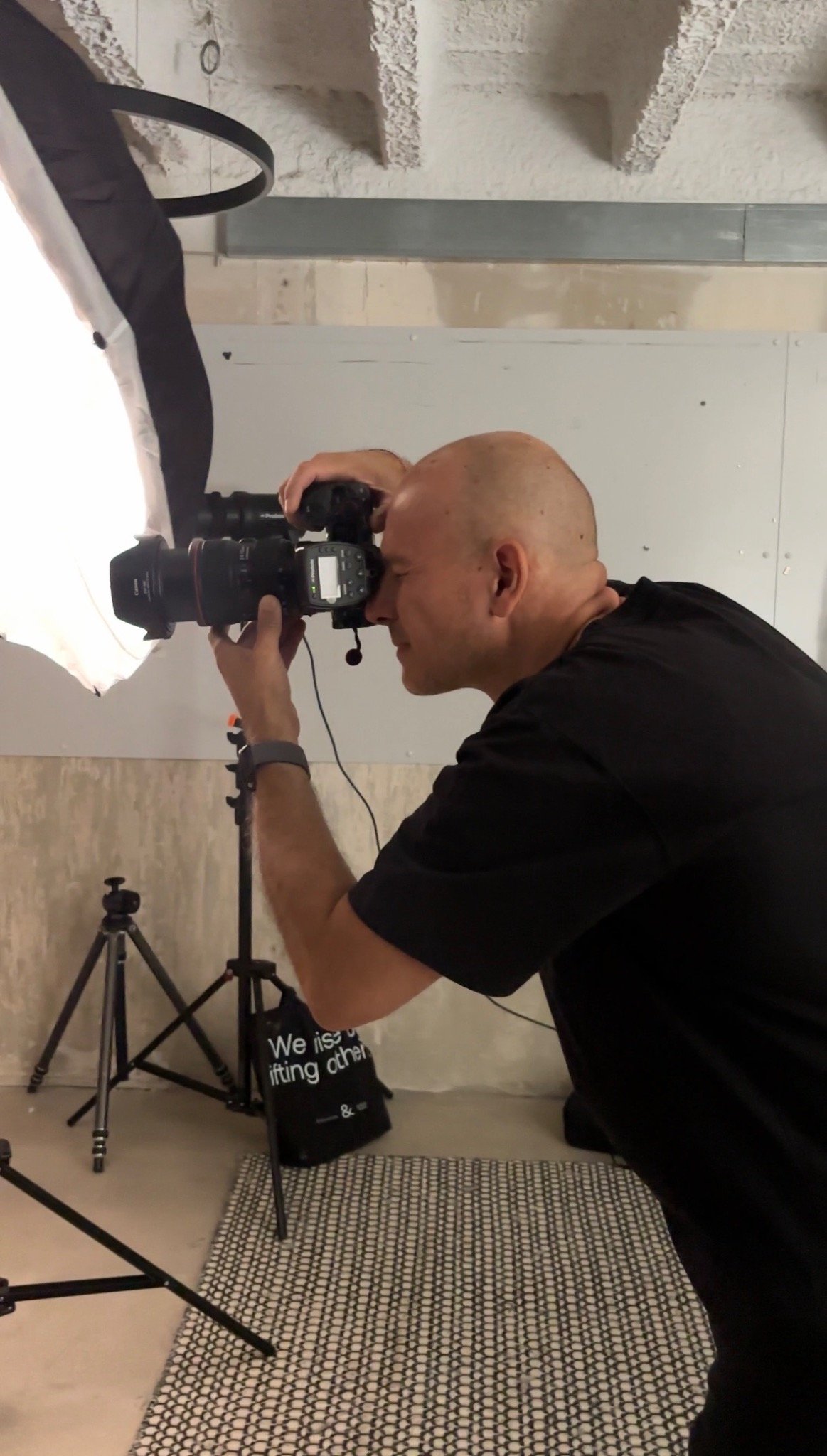Sven Cichowicz fotografiert mit einer Kamera vor dem Gesicht neben einer großen Studiolampe.