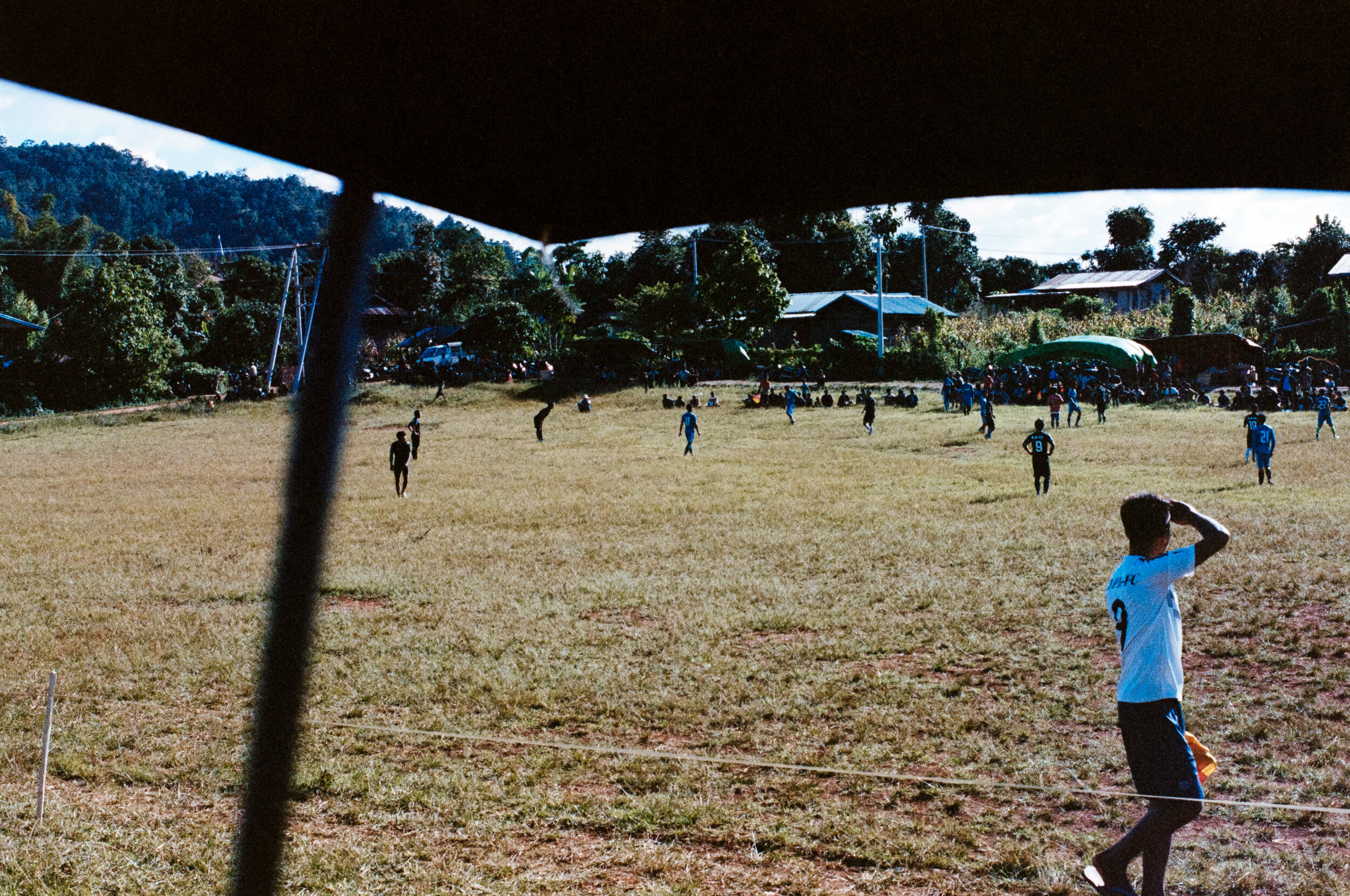  A annual soccer tournament is held among the villages in Kayah state. Spectators hiding under umbrellas because of the sun… A sun so strong it would burn the skin in an instant. It’s common this time of year…  One of the matches in Pan Pet. For some