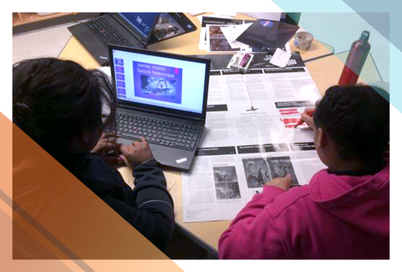 Two students engage in a Webb Telescope research activity with a laptop and printed information at a Barclay after school event.