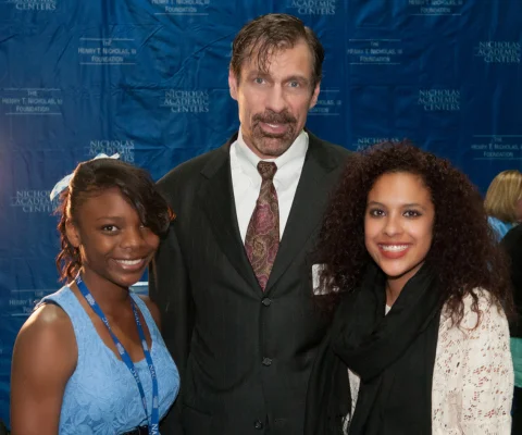 Henry T. Nicholas, III, Ph.D., joins Nicholas Academic Center (NAC) students Erin Davis (left) and Jennifer Nava at the 4th Annual Thanksgiving Dinner Celebration. The Broadcom Co-Founder and former CEO told the more than 300 students and their families: "One hundred percent of our students go on to college, and we're going to ensure that every one of them earns a degree." (Photo: Business Wire)