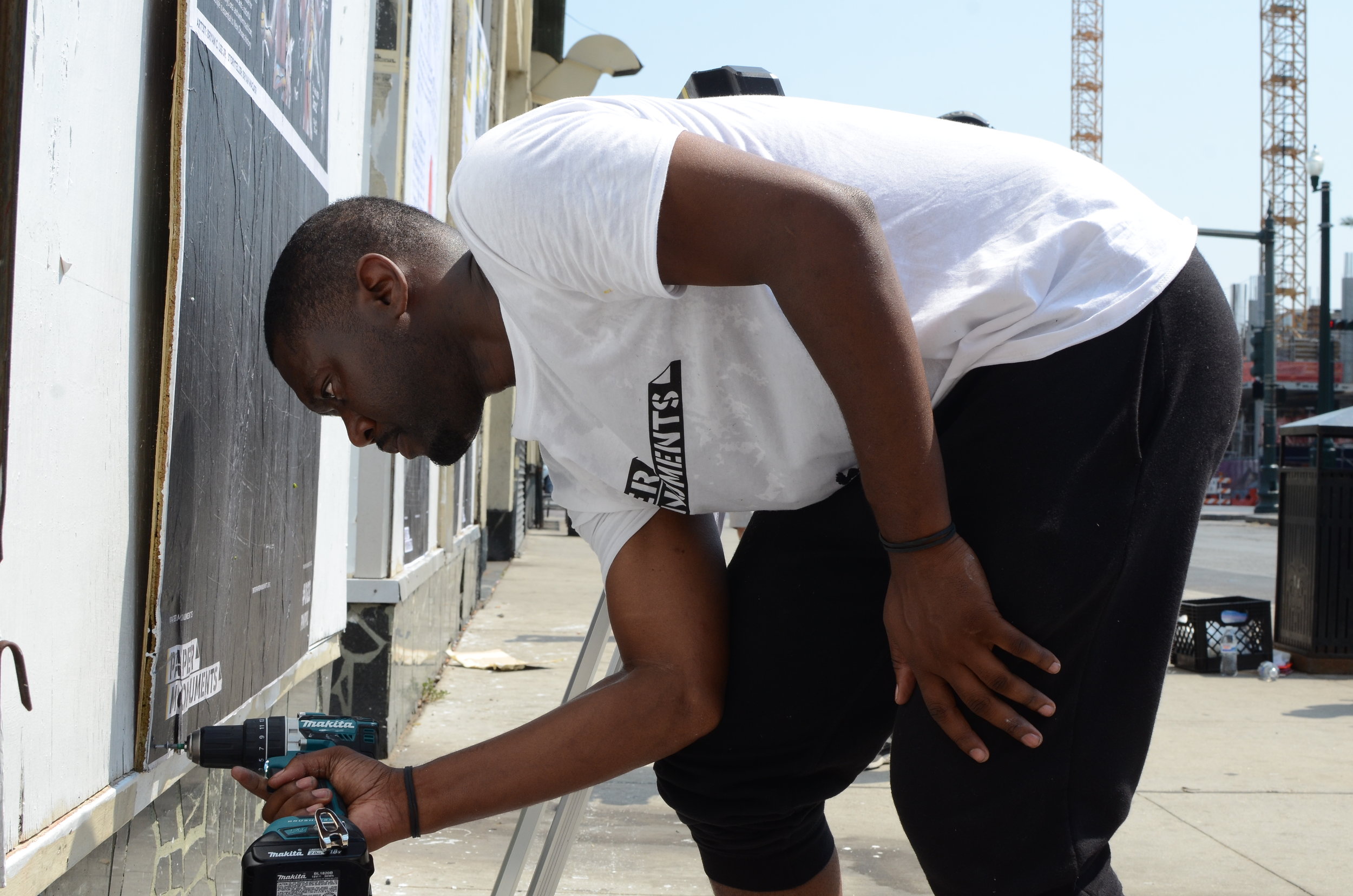  Paper Monuments co-director Bryan Lee Jr. installs a poster at the Rampart site.  