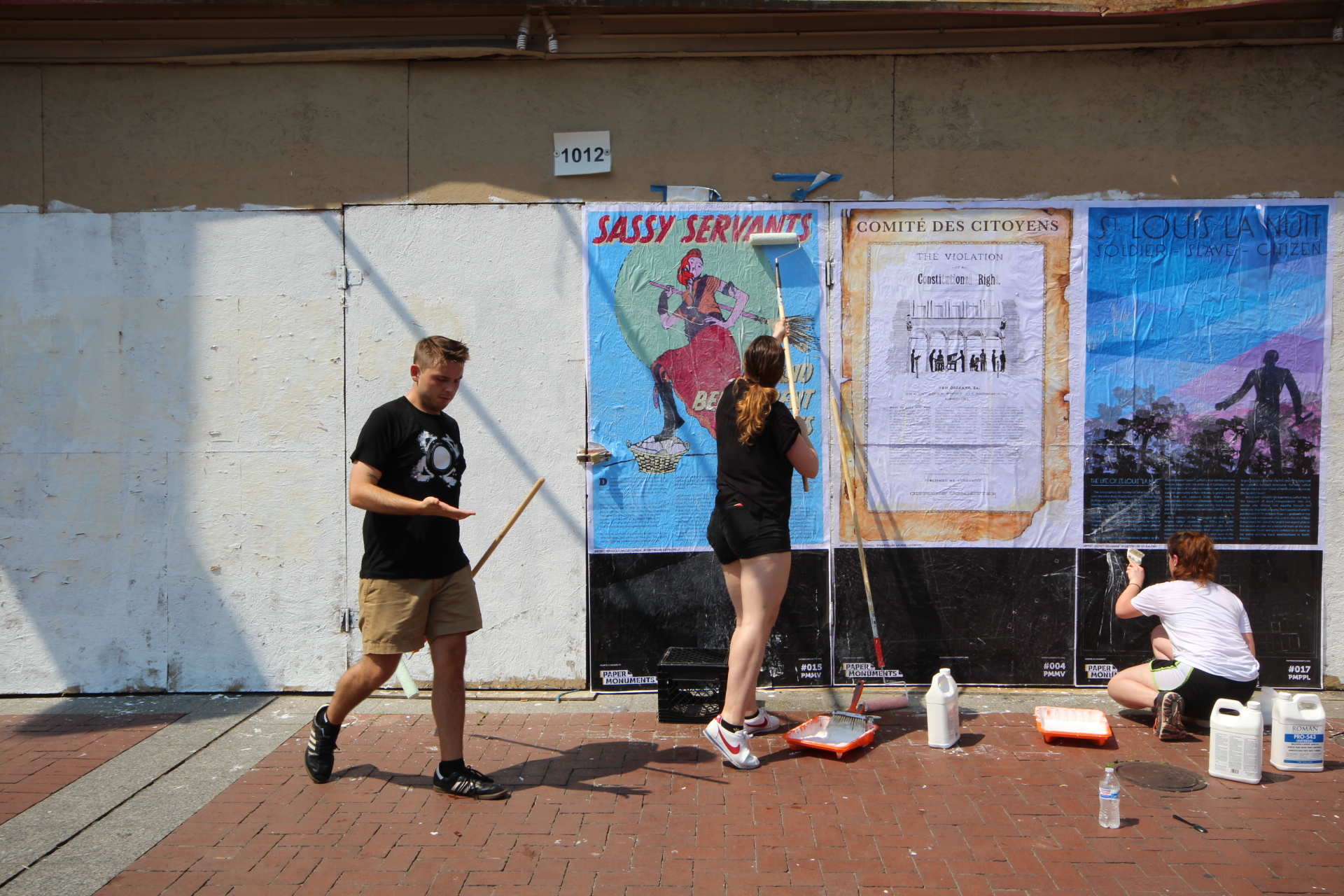  Paper Monuments volunteers Corbin and Maggie and team member Isa Siegel install poster panels at the Canal Street site. 