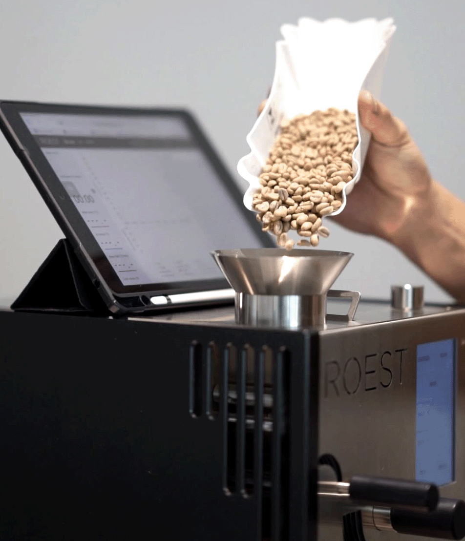 loading green coffee beans into the ROEST L200 Ultra sample roaster, preparing for precision small-batch roasting in a professional lab