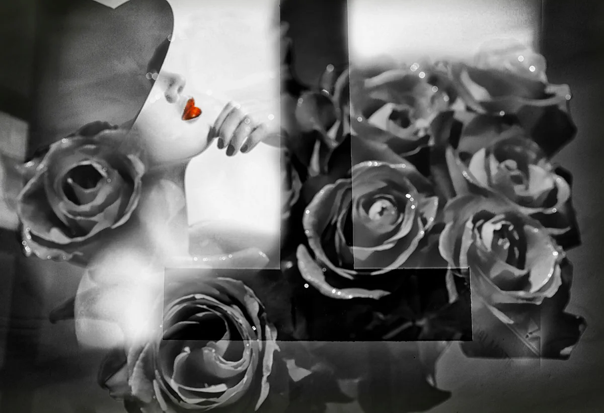Black and white photo of a bust of a woman with roses around her, with a red heart on her lips and a hand on her chin.