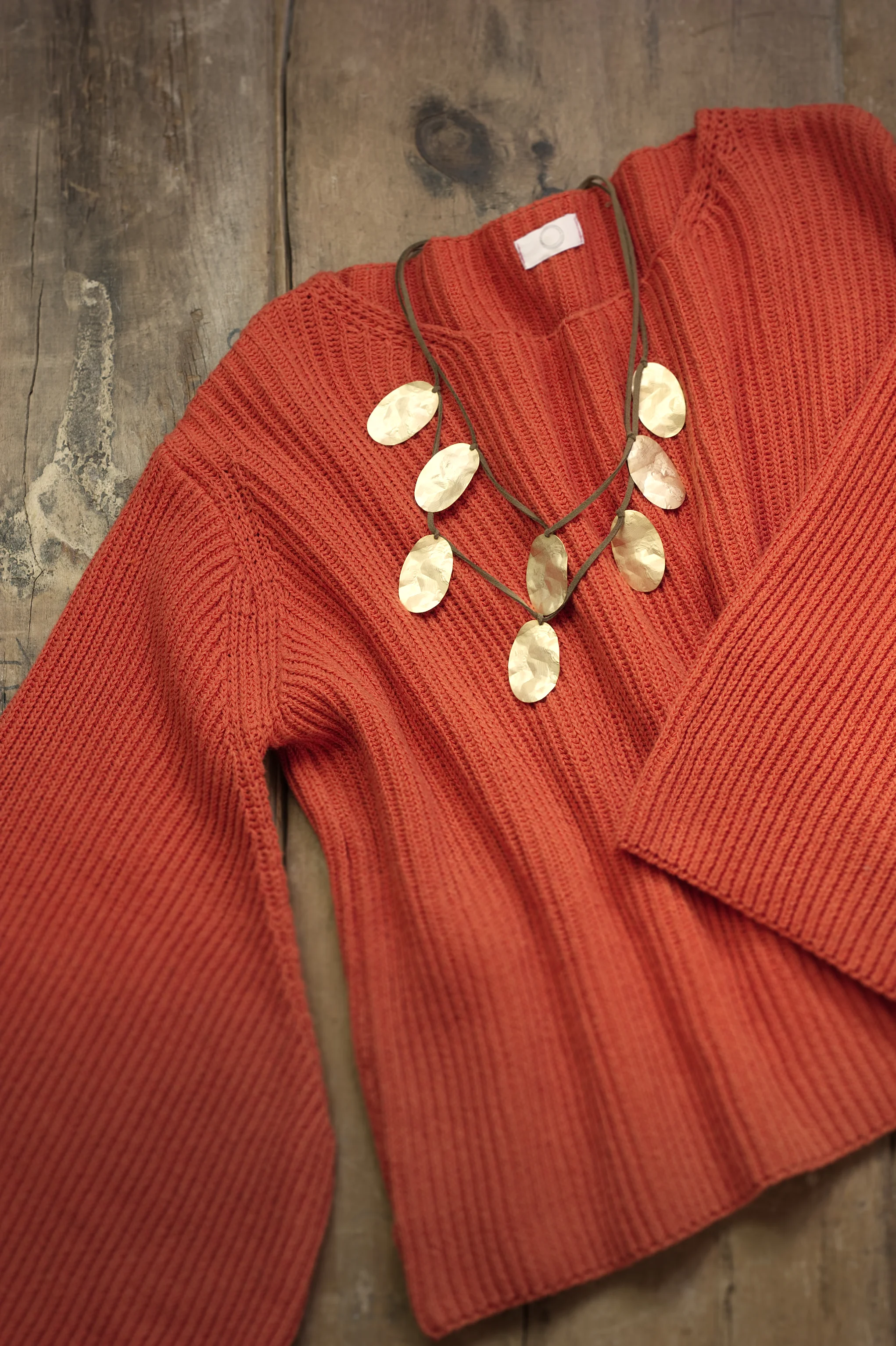 Cosy, orange jumper with bell sleeves, teamed with a gold-toned necklace.