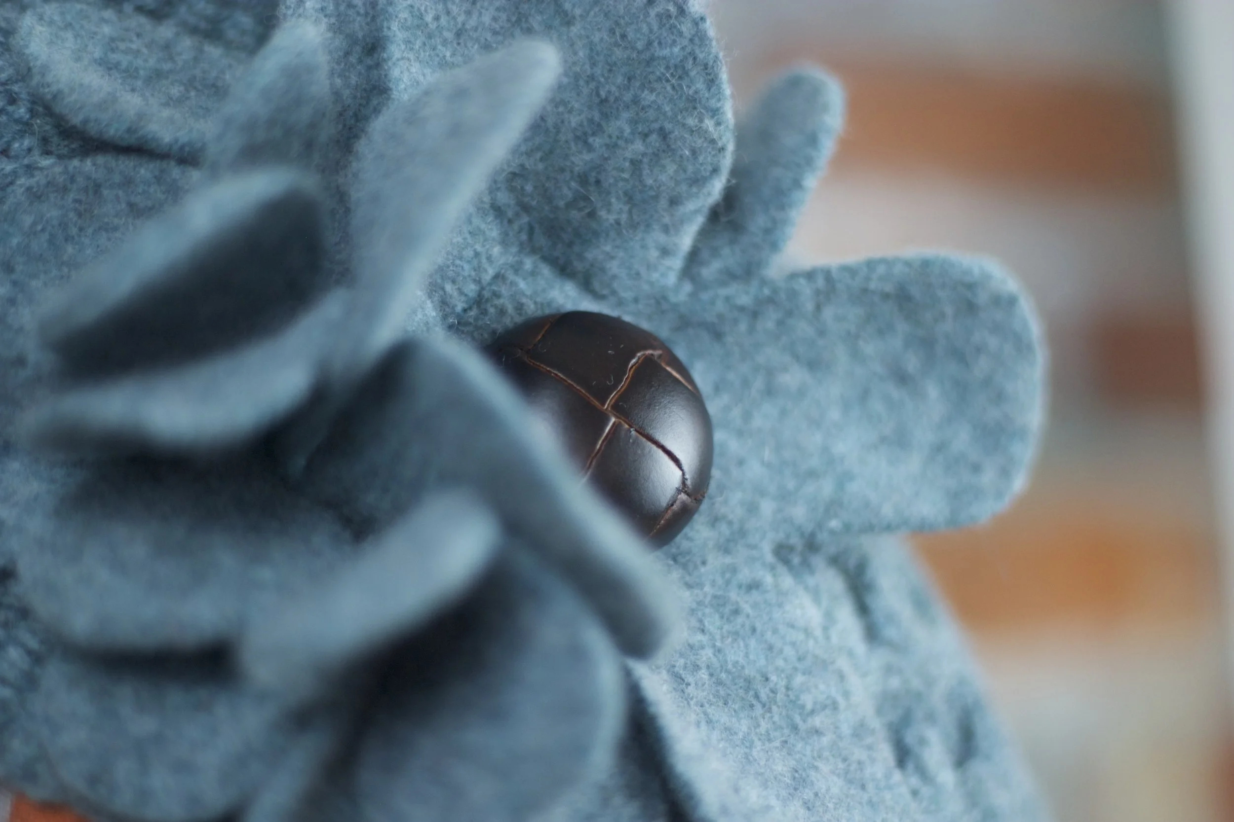 Detail of a felted flower with leather-effect button centre.