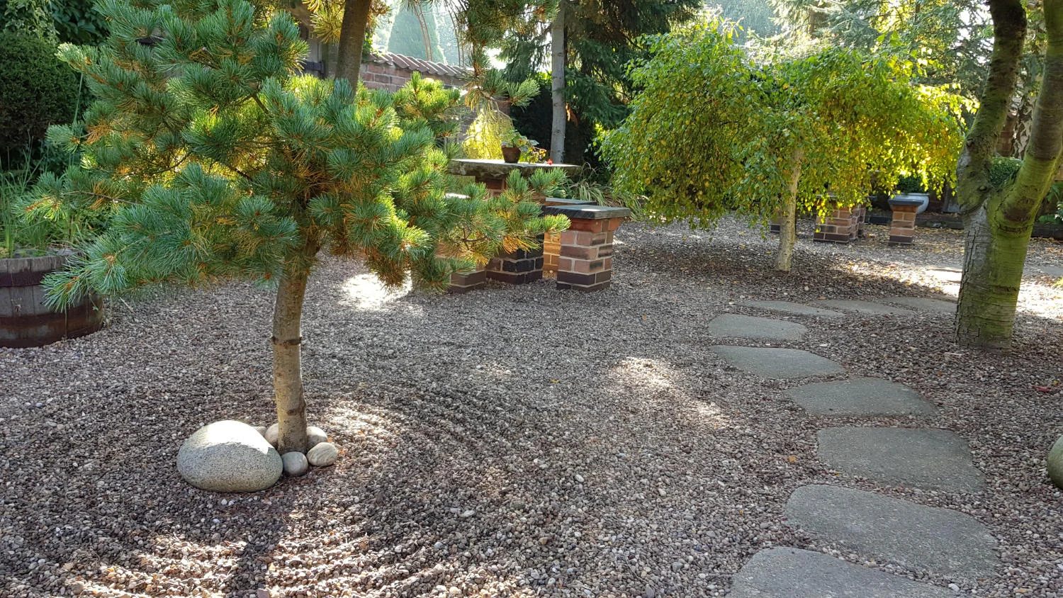 The Japanese-style tea garden with raked gravel around the trunk of a tree.