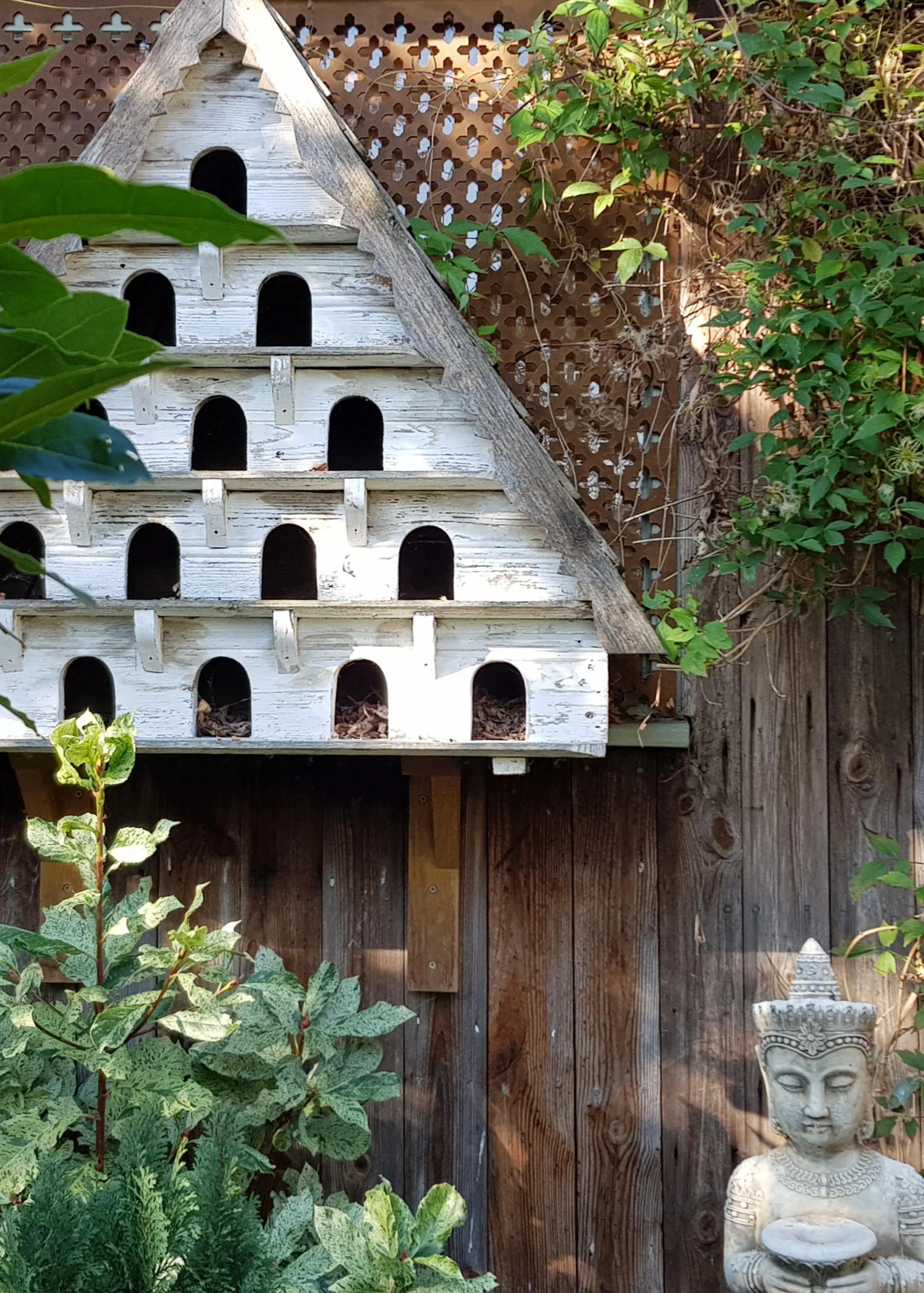 Triangular, white painted bird house with five floors.