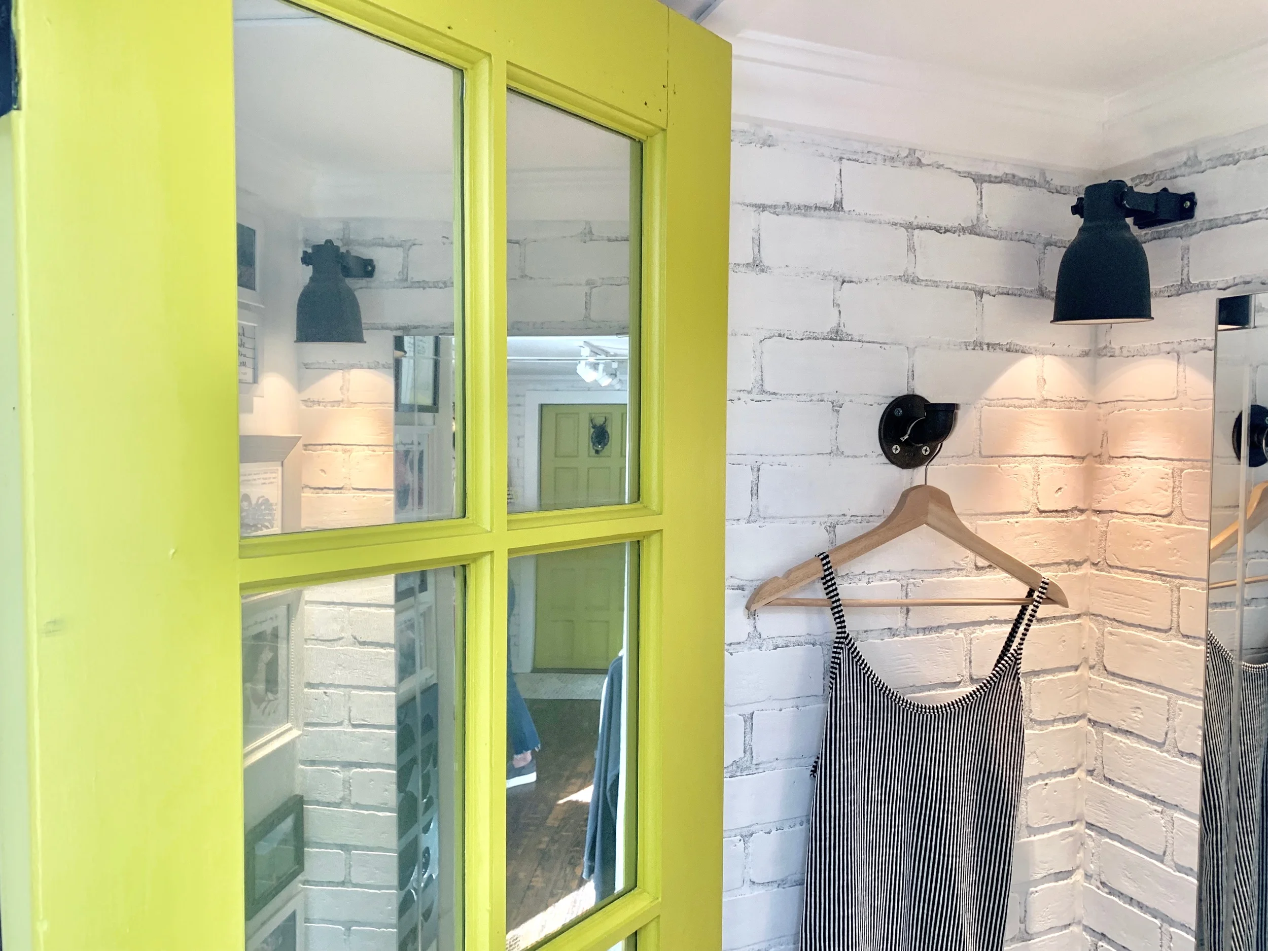 Mirror paint was sprayed onto interior & exterior of fitting room door to maximize light; sconces & hooks installed
