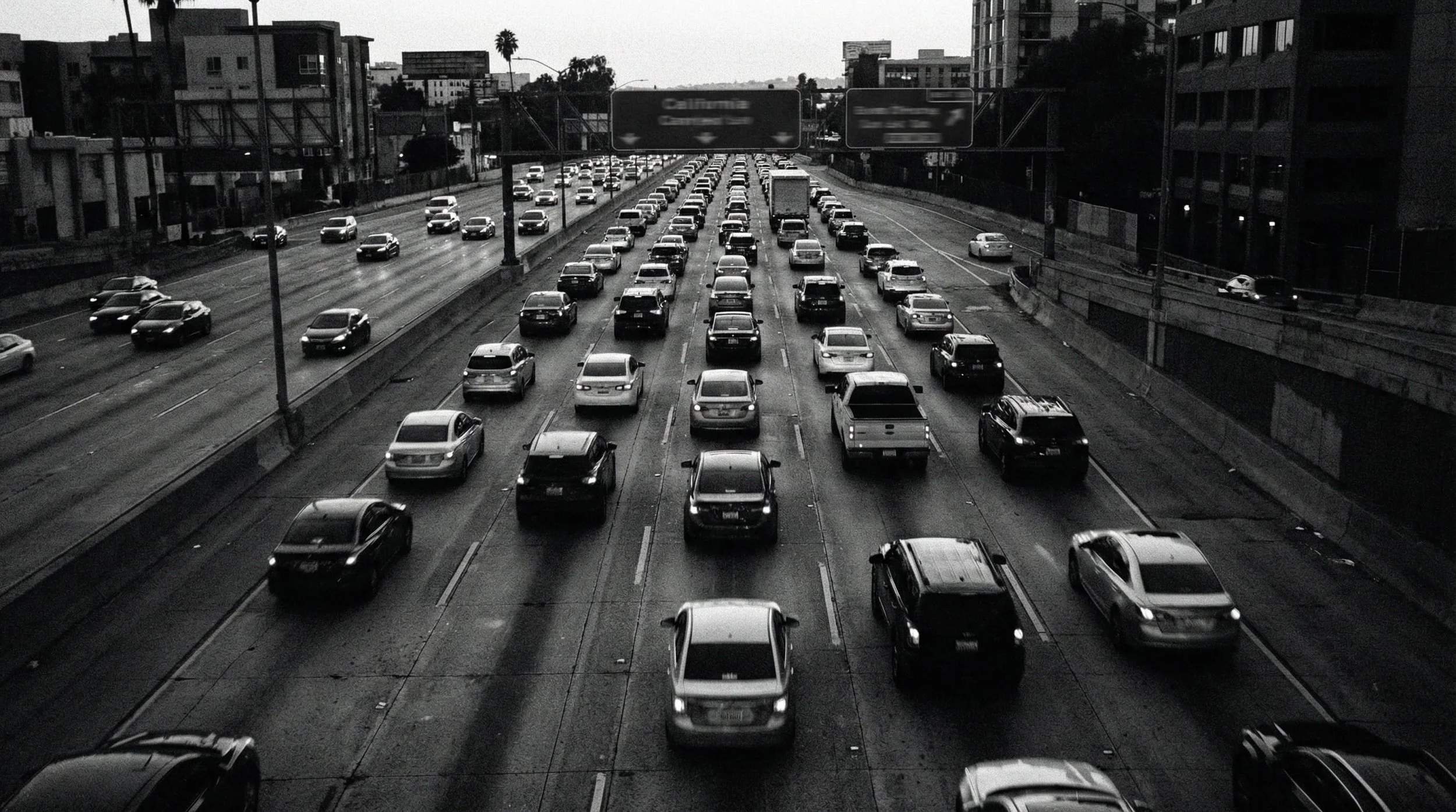 Black-and-white aerial view of heavy traffic on a multi-lane urban freeway.